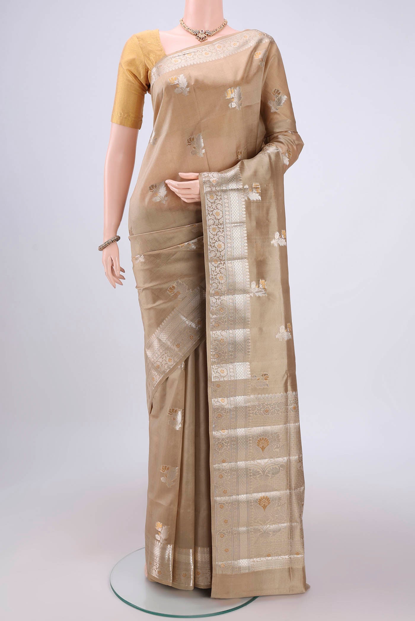 Beige Banarasi Raw Silk Saree with Zari Butta on the body and Zari Border.  displayed on a mannequin