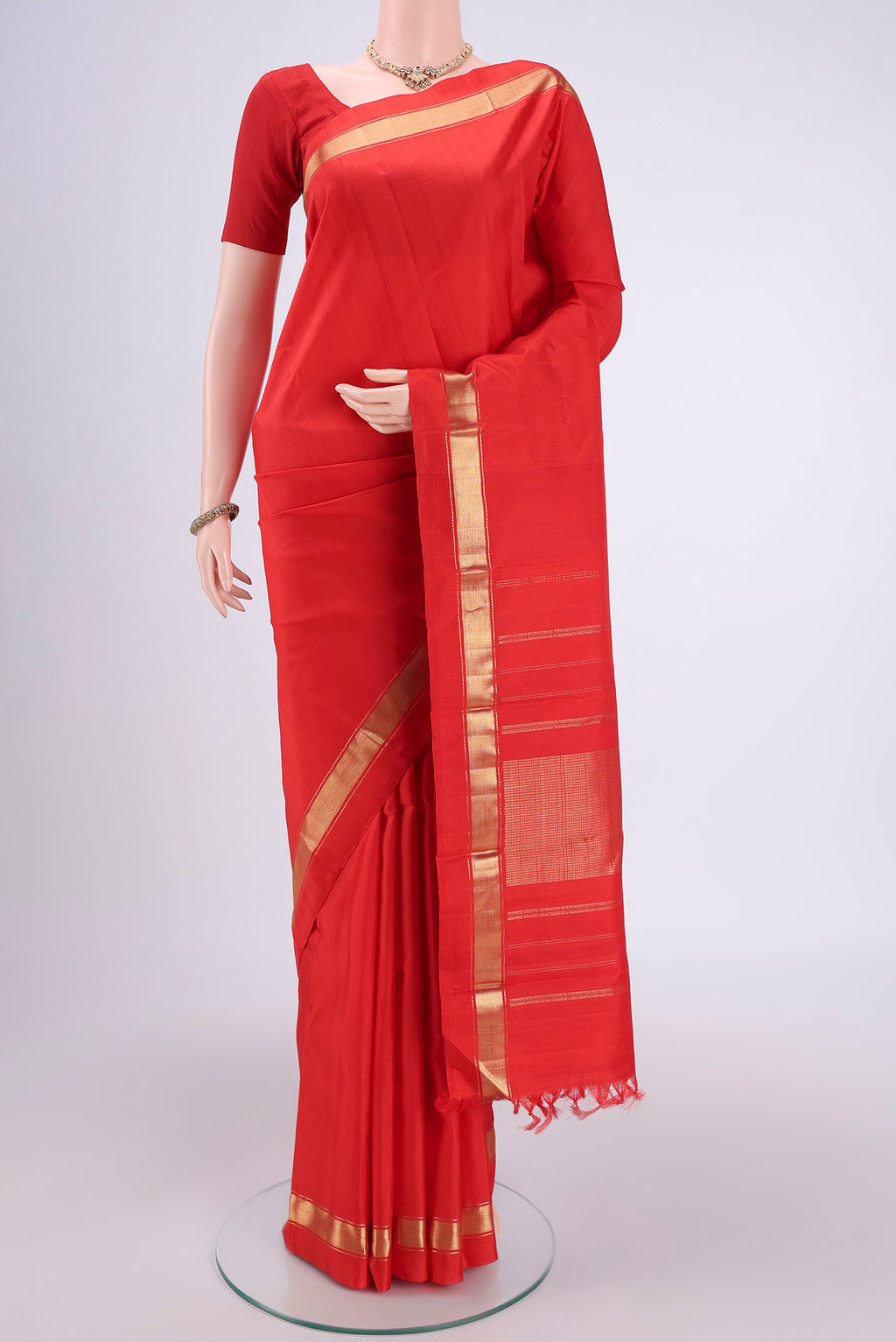 Orange Kanjivaram Silk Saree with Zari Butta on the body and One Side Border.  displayed on a mannequin
