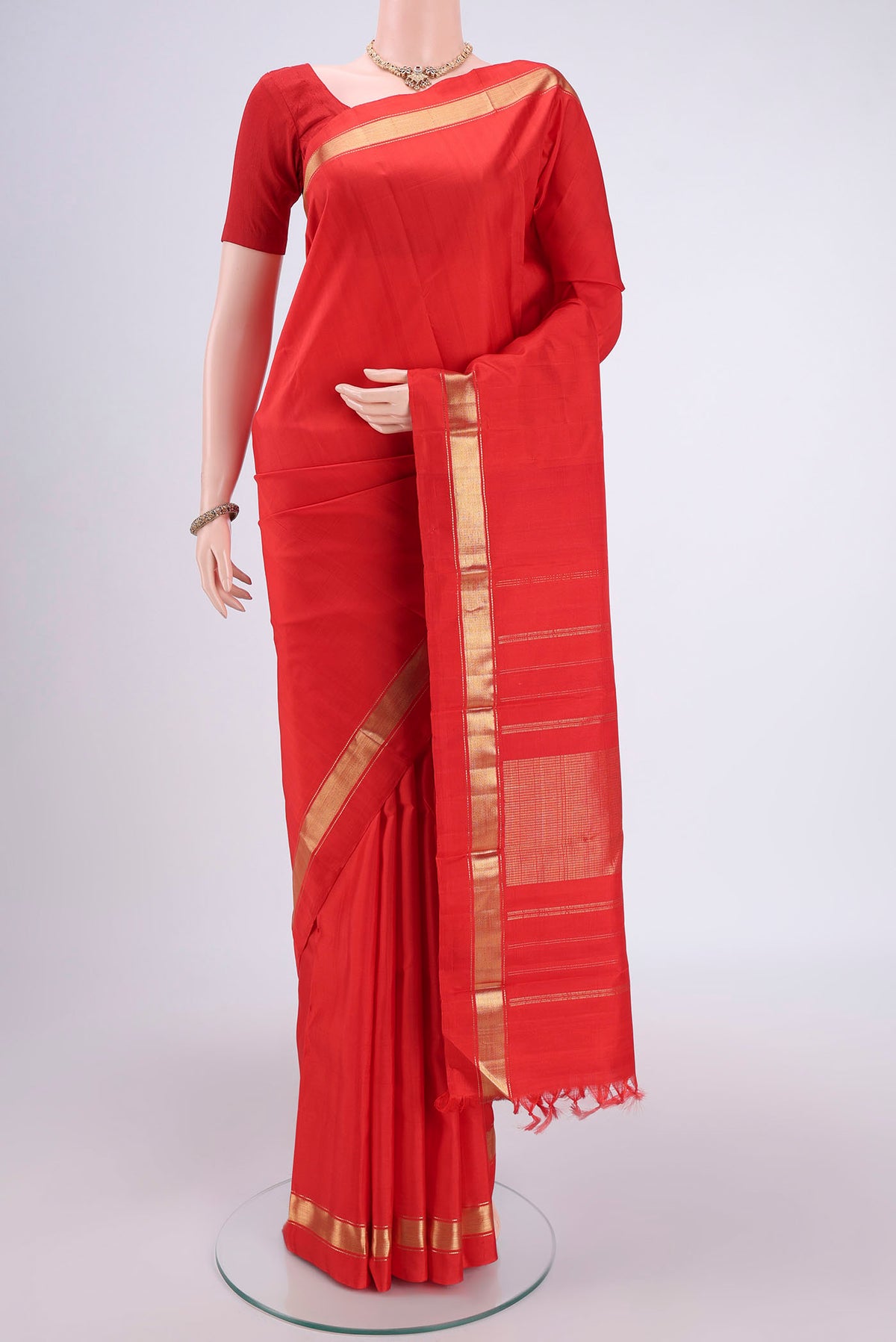 Orange Kanjivaram Silk Saree with Zari Butta on the body and One Side Border.  displayed on a mannequin