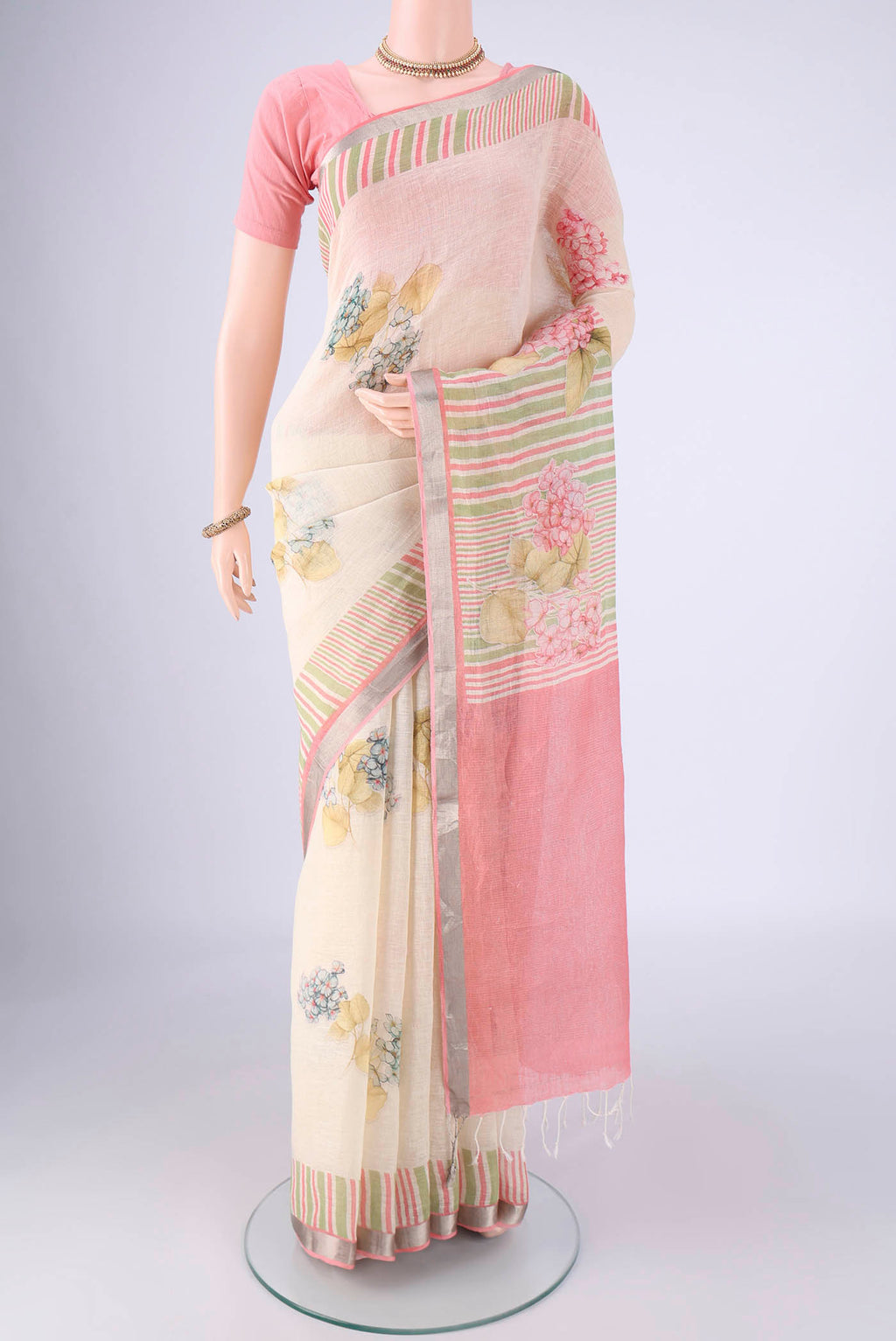 Off White Linen Saree with Floral Print on the body and Zari Border.  displayed on a mannequin