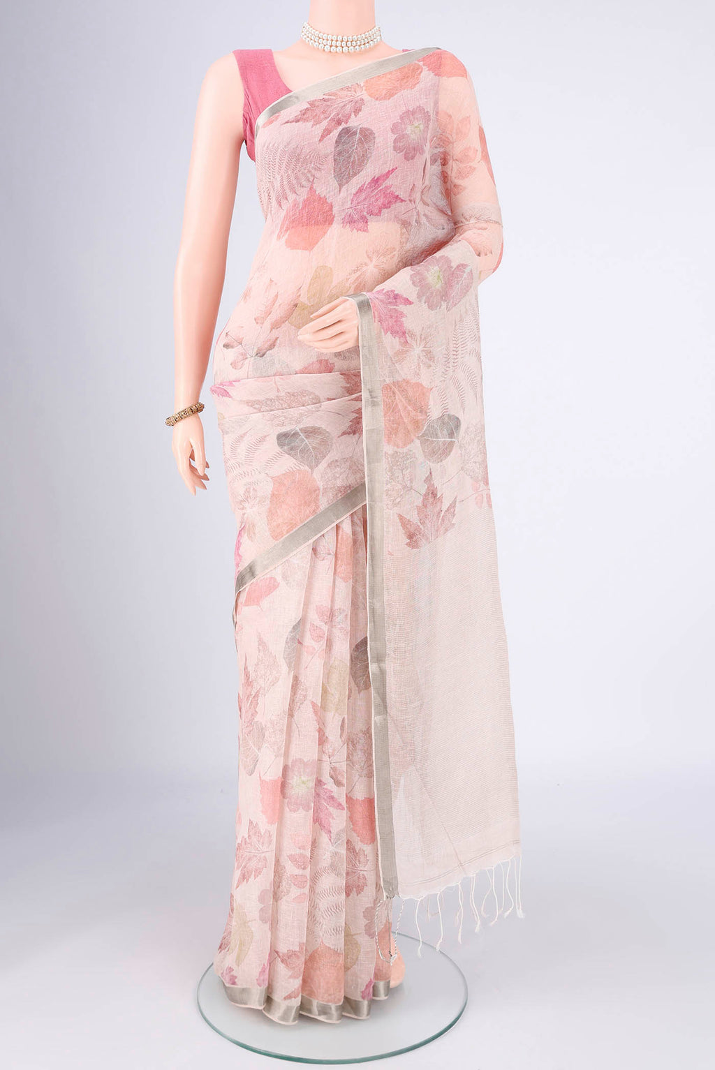 Rose Gold Linen Saree with Printed design on the body and Zari Border.  displayed on a mannequin