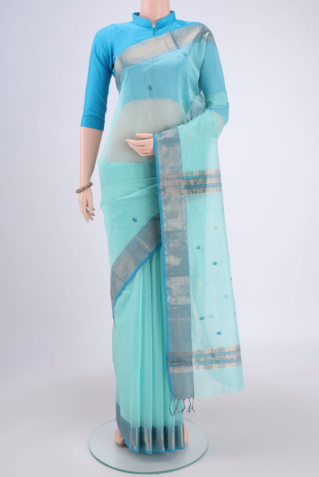 Sky Blue Maheshwari Silk Cotton Saree with Zari And Thread Butta on the body and Zari Border.  displayed on a mannequin