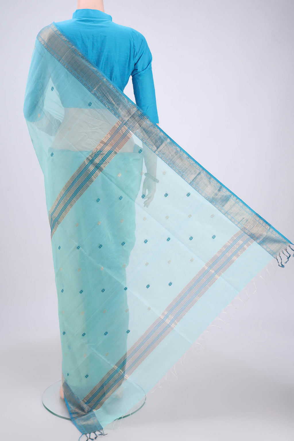 Flat view of Sky Blue Maheshwari Silk Cotton Saree with Zari And Thread Butta on the body and Zari Border. 