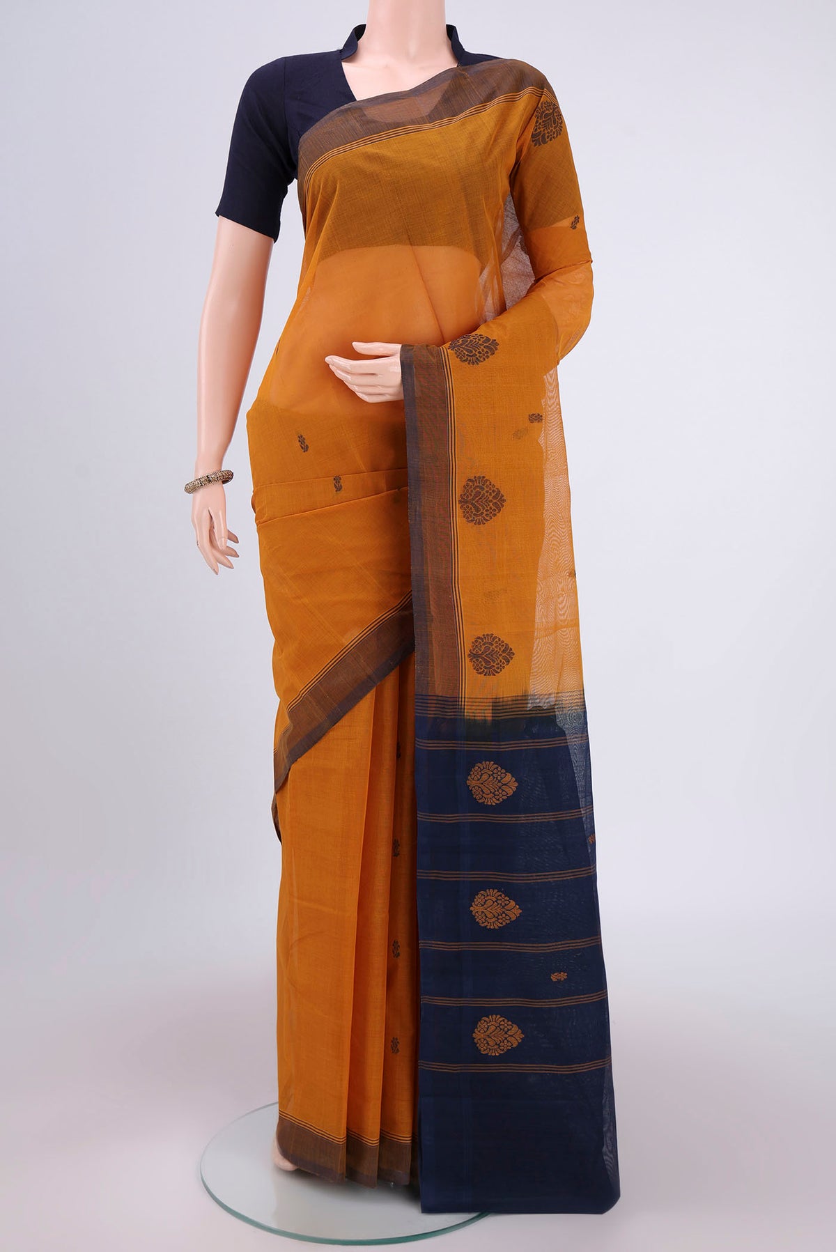 Mustard Kanchi Cotton Saree with Thread Butta on the body and Thread Border.  displayed on a mannequin