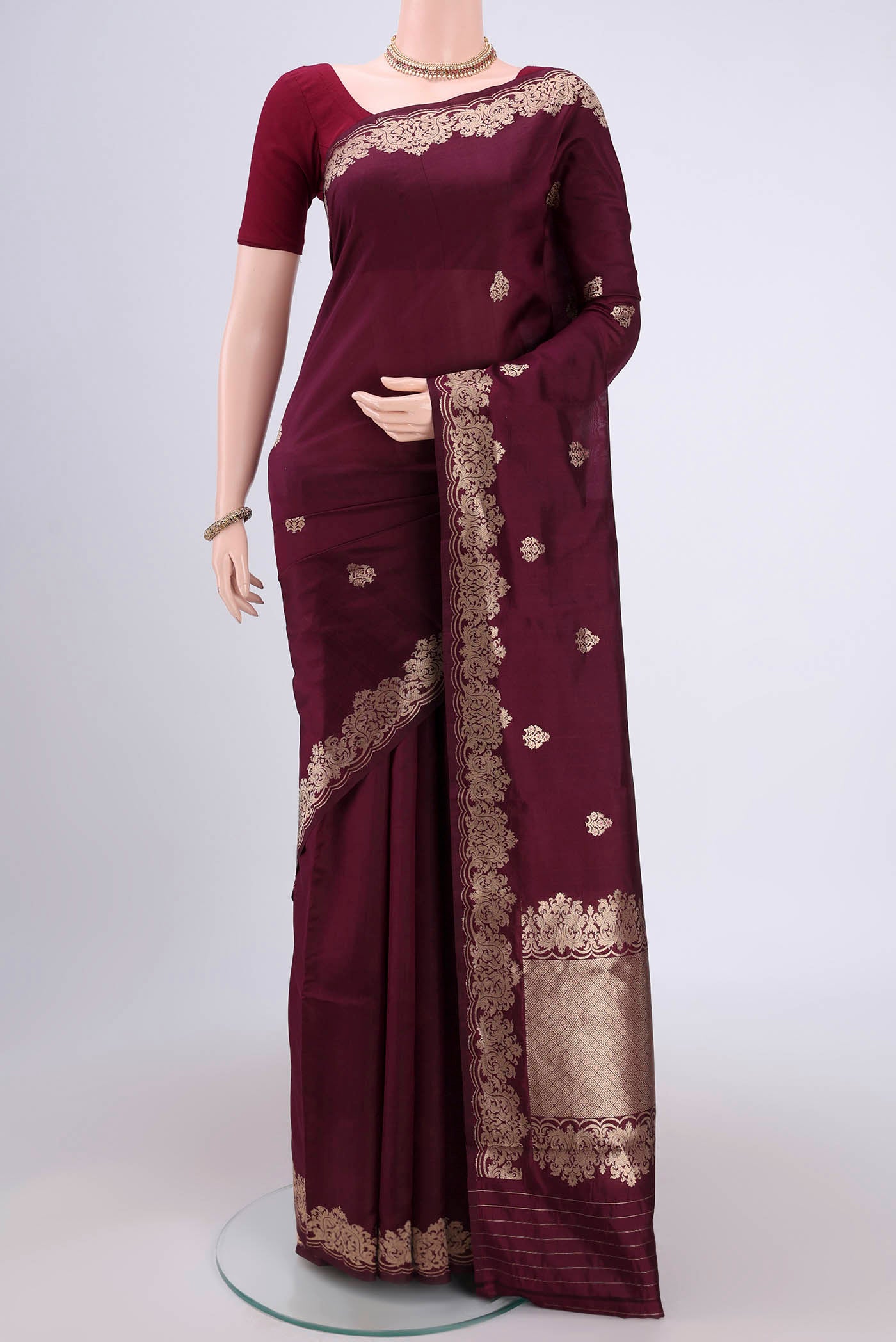 Burgundy Banarasi Katan Silk Saree with Zari Butta on the body and Zari Border.  displayed on a mannequin