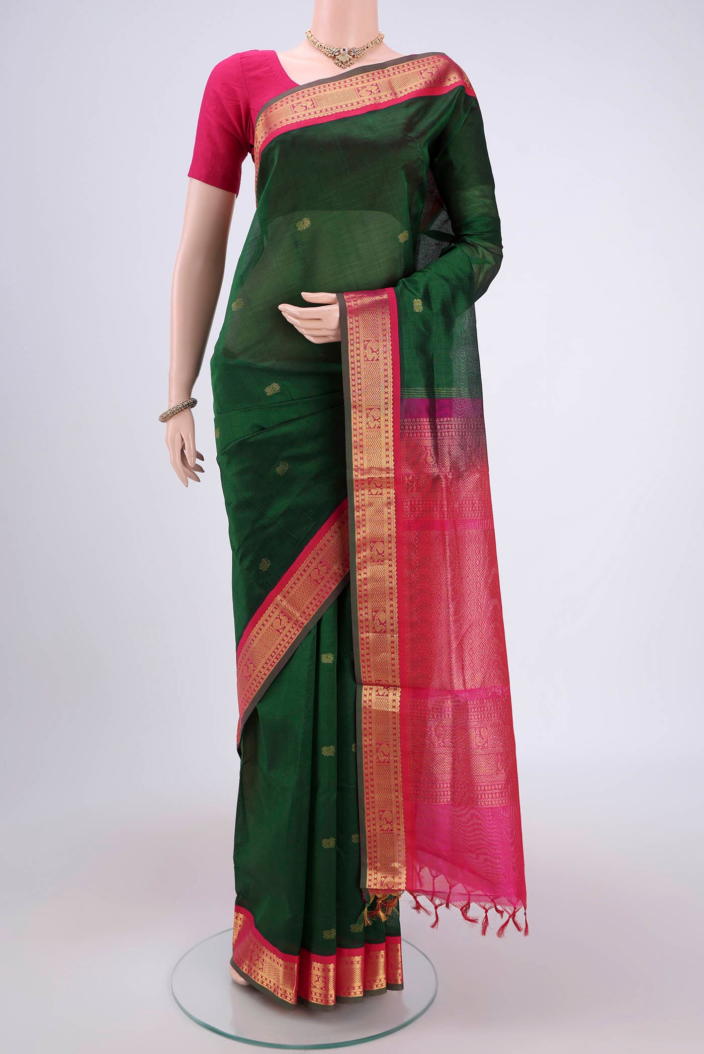Bottle Green Silk Cotton Saree with Zari Butta on the body and Zari Border.  displayed on a mannequin