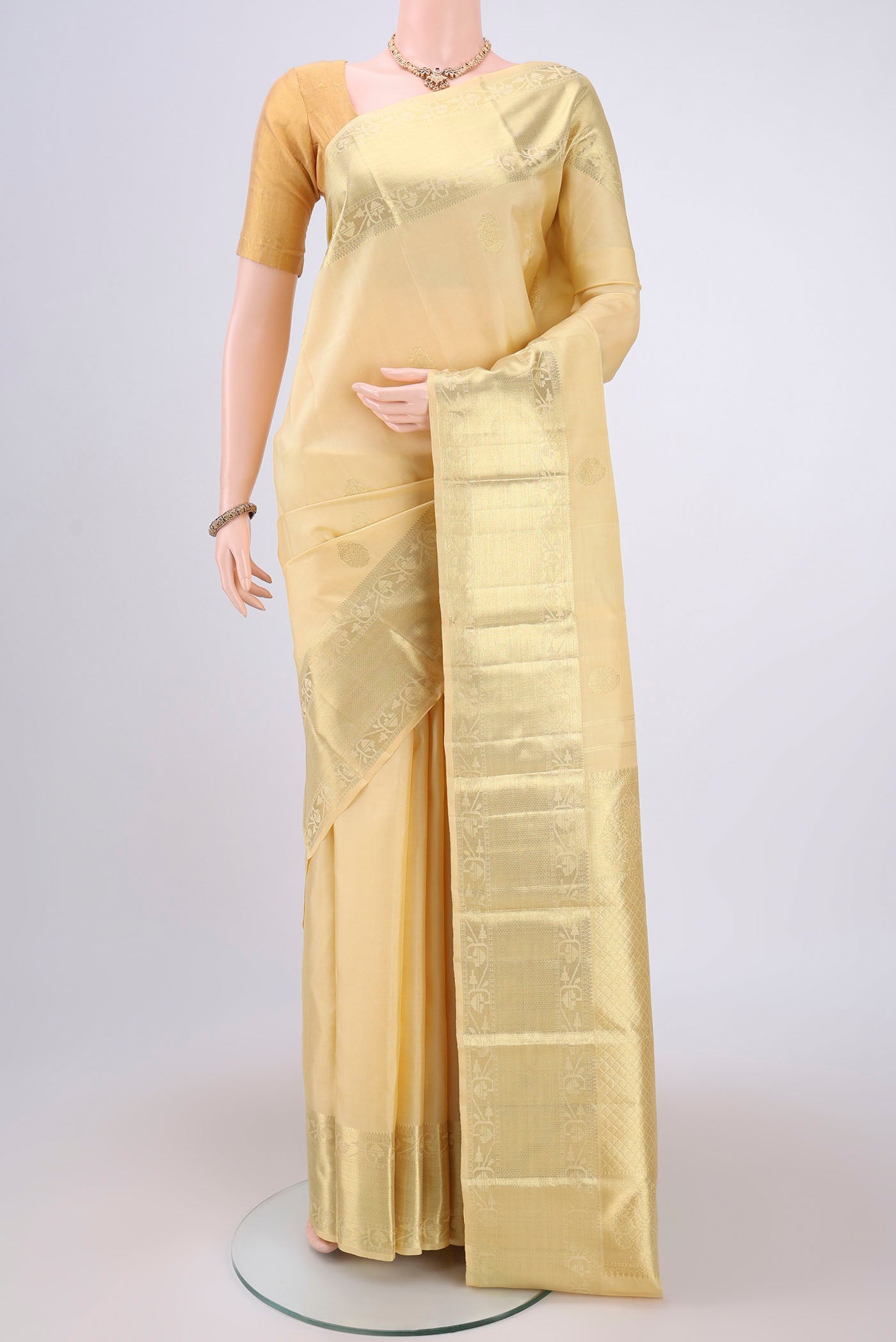 Cream Kanchipuram Silk Saree with Zari Butta on the body and Zari Border.  displayed on a mannequin