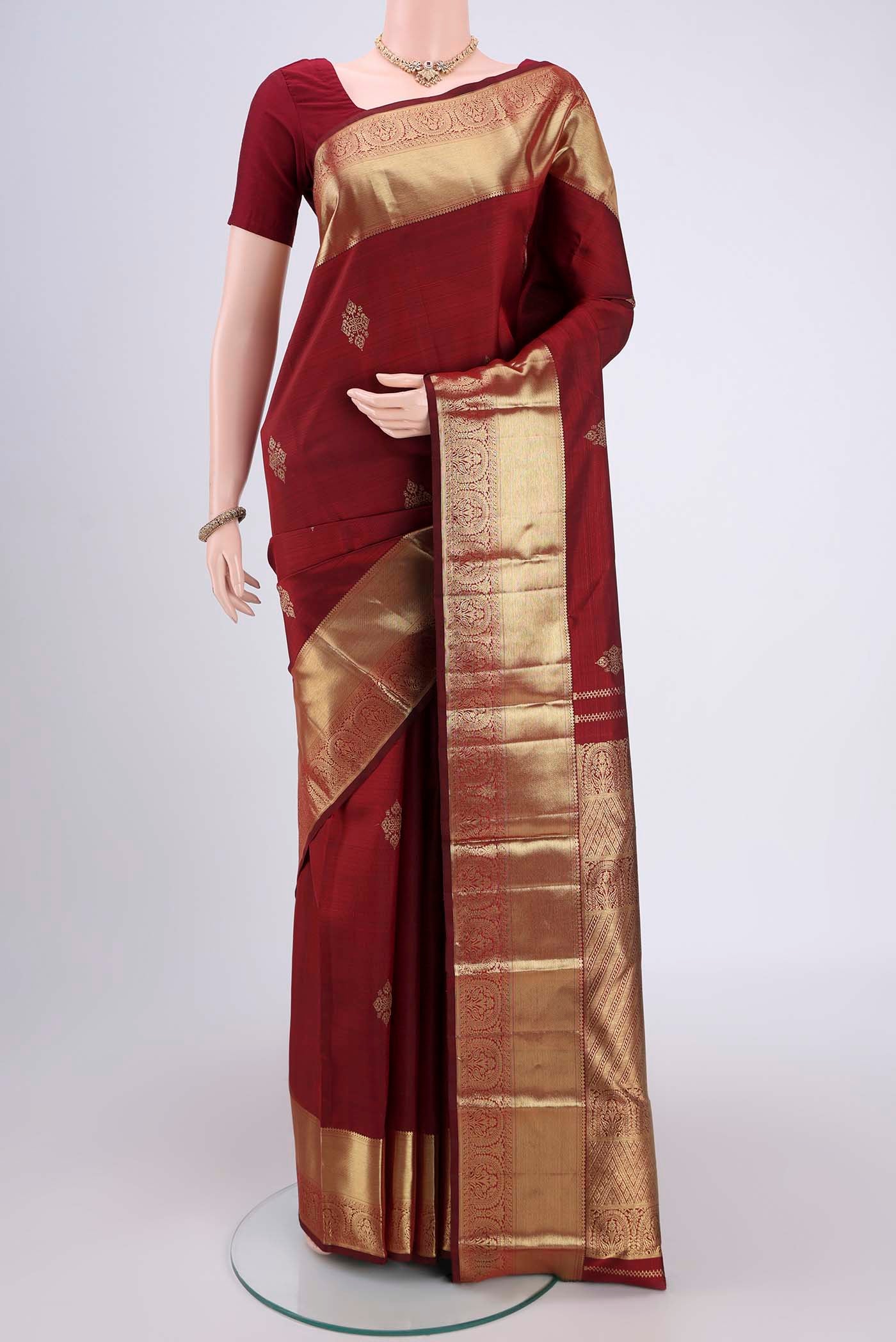 Maroon Kanchipuram Silk Saree with Zari Butta on the body and Zari Border.  displayed on a mannequin