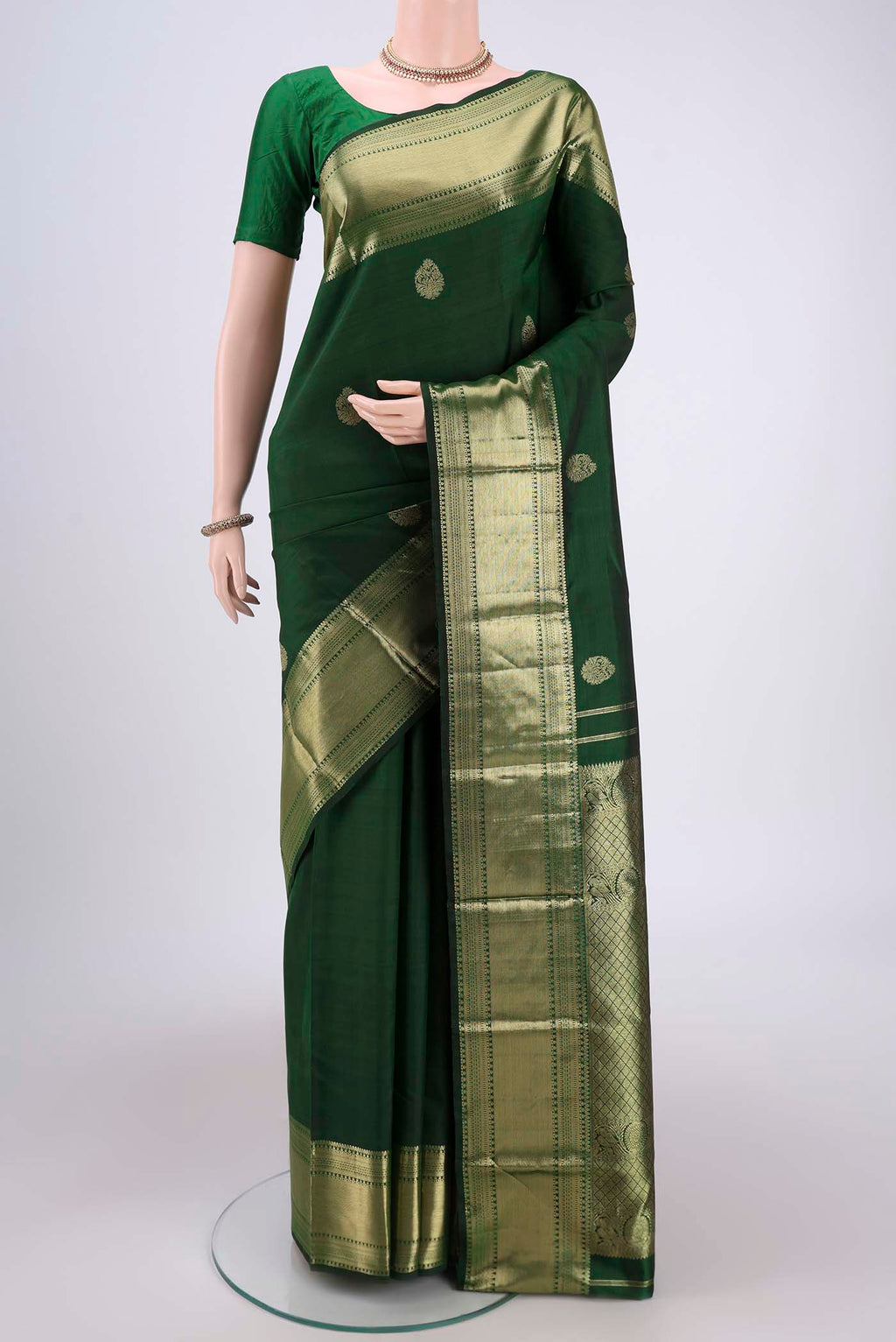 Bottle Green Kanchipuram Silk Saree with Zari Butta on the body and Zari Border.  displayed on a mannequin
