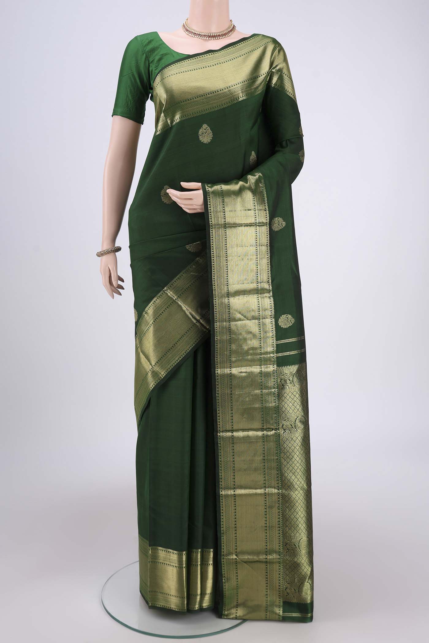 Bottle Green Kanchipuram Silk Saree with Zari Butta on the body and Zari Border.  displayed on a mannequin