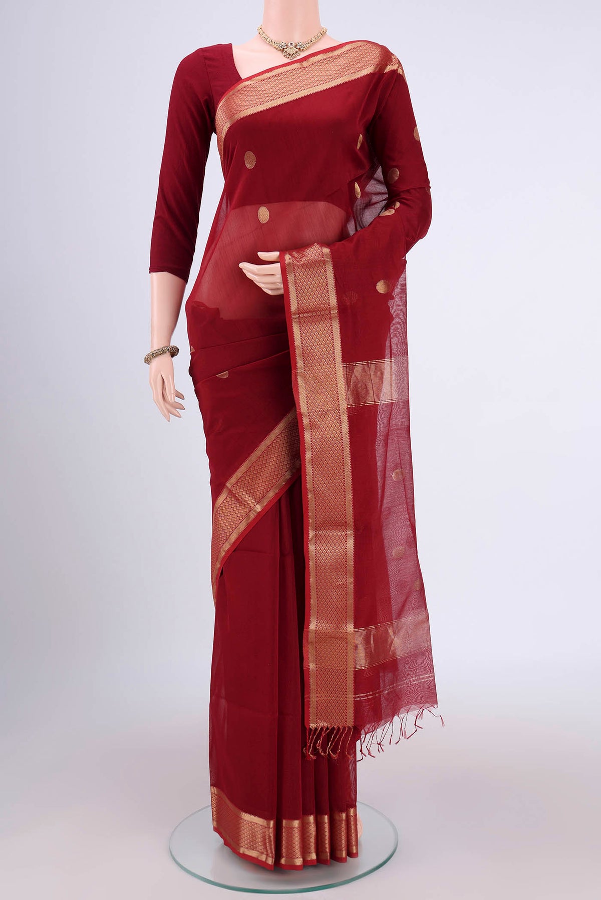 Maroon Maheshwari Silk Cotton Saree with Polka Dots on the body and Zari Border.  displayed on a mannequin