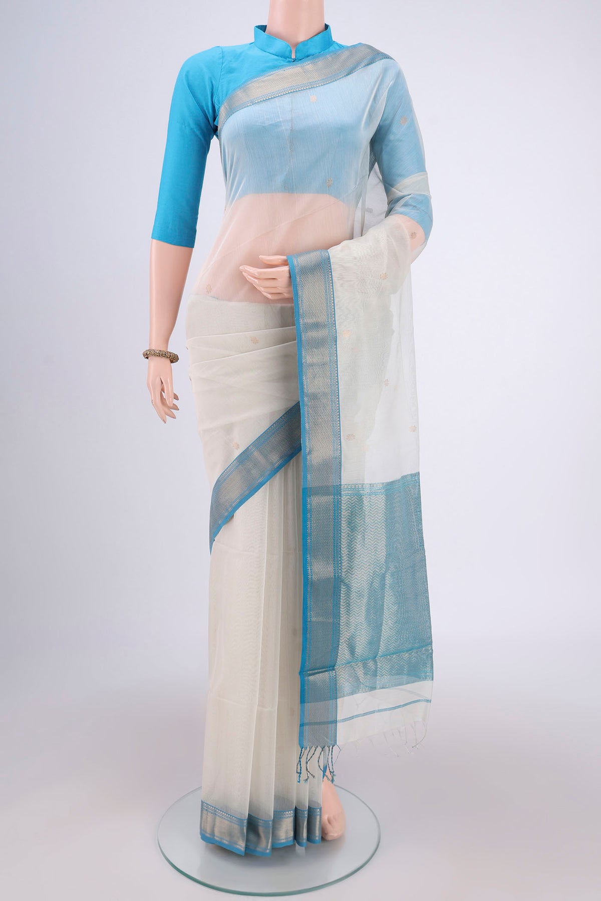 Off White Maheshwari Silk Cotton Saree with Zari Butta on the body and Zari Border.  displayed on a mannequin