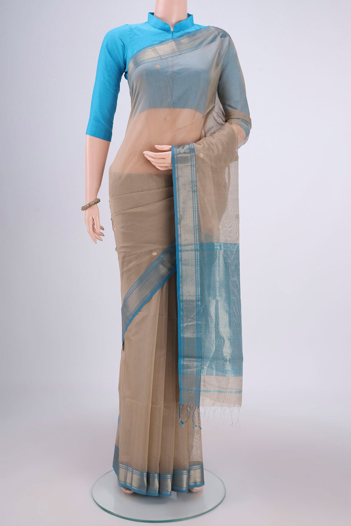 Dark Beige Maheshwari Silk Cotton Saree with Zari And Thread Butta on the body and Zari Border.  displayed on a mannequin
