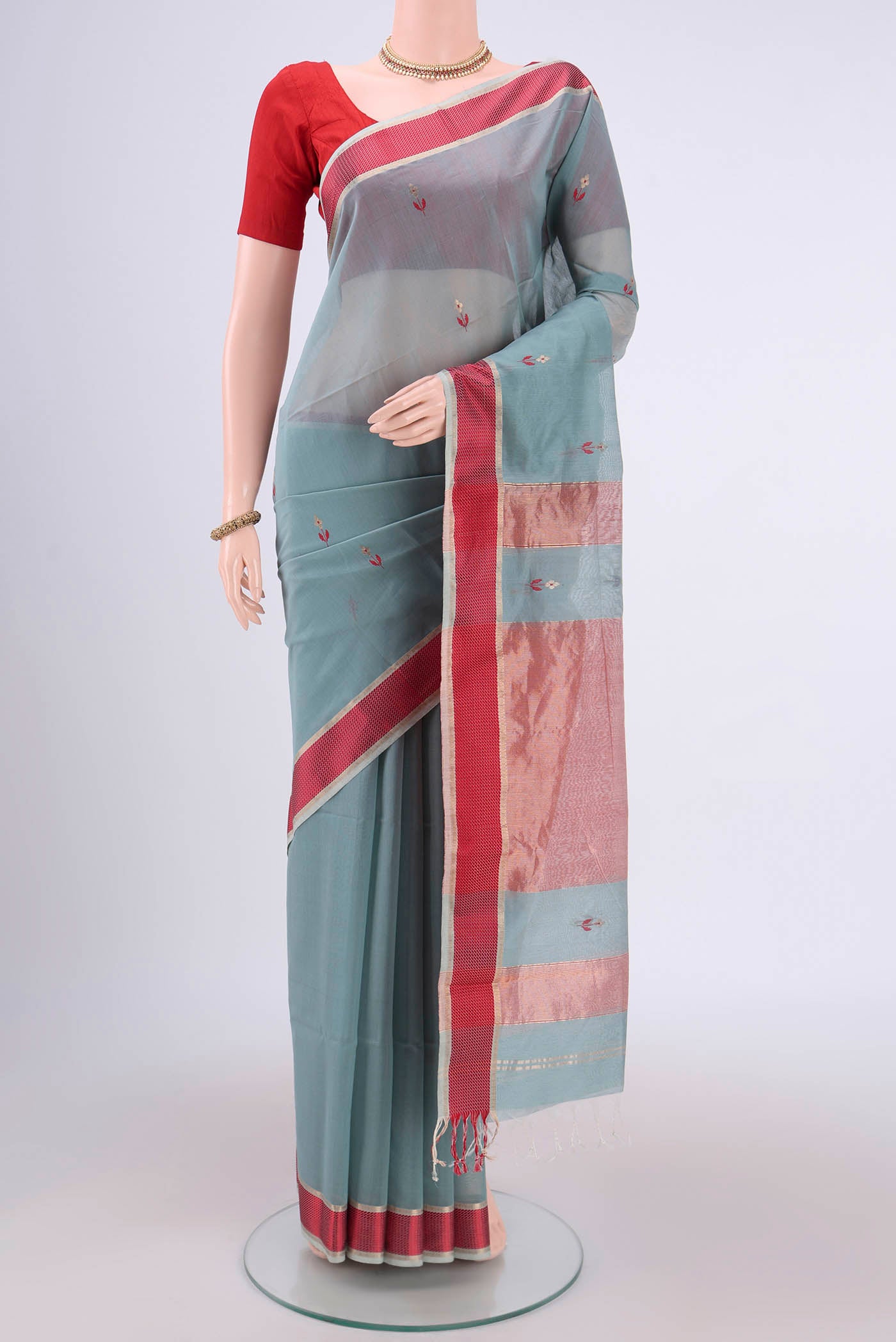 Sage Green Maheshwari Silk Cotton Saree with Zari And Thread Butta on the body and Zari Border.  displayed on a mannequin