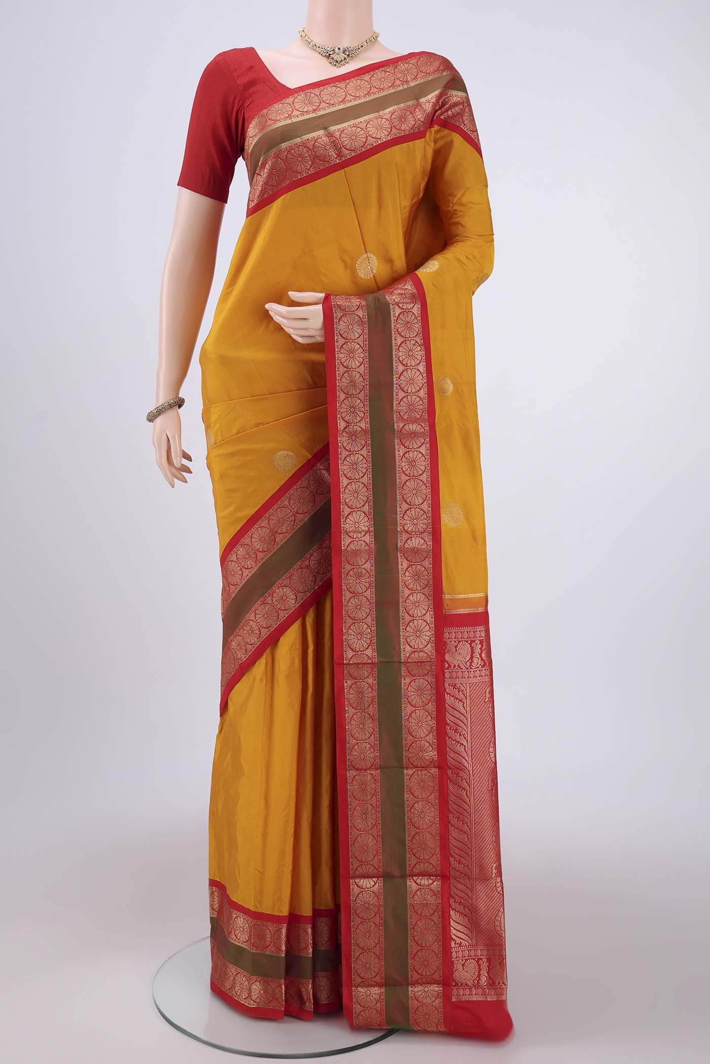 Mustard Bangalore Silk Saree with Zari Butta on the body and Temple Border.  displayed on a mannequin