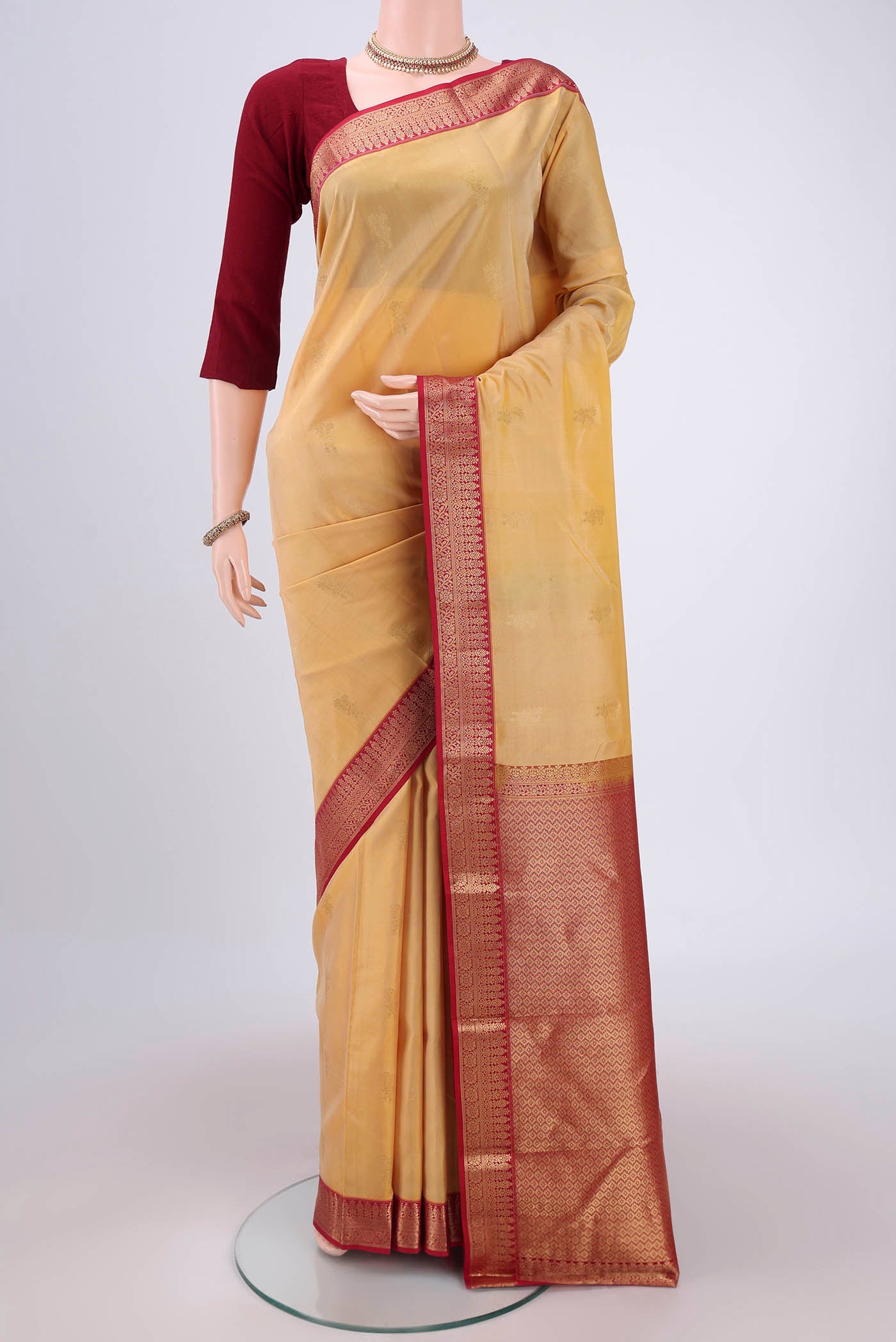 Cream Kanchipuram Silk Saree with Zari Butta on the body and Zari Border.  displayed on a mannequin