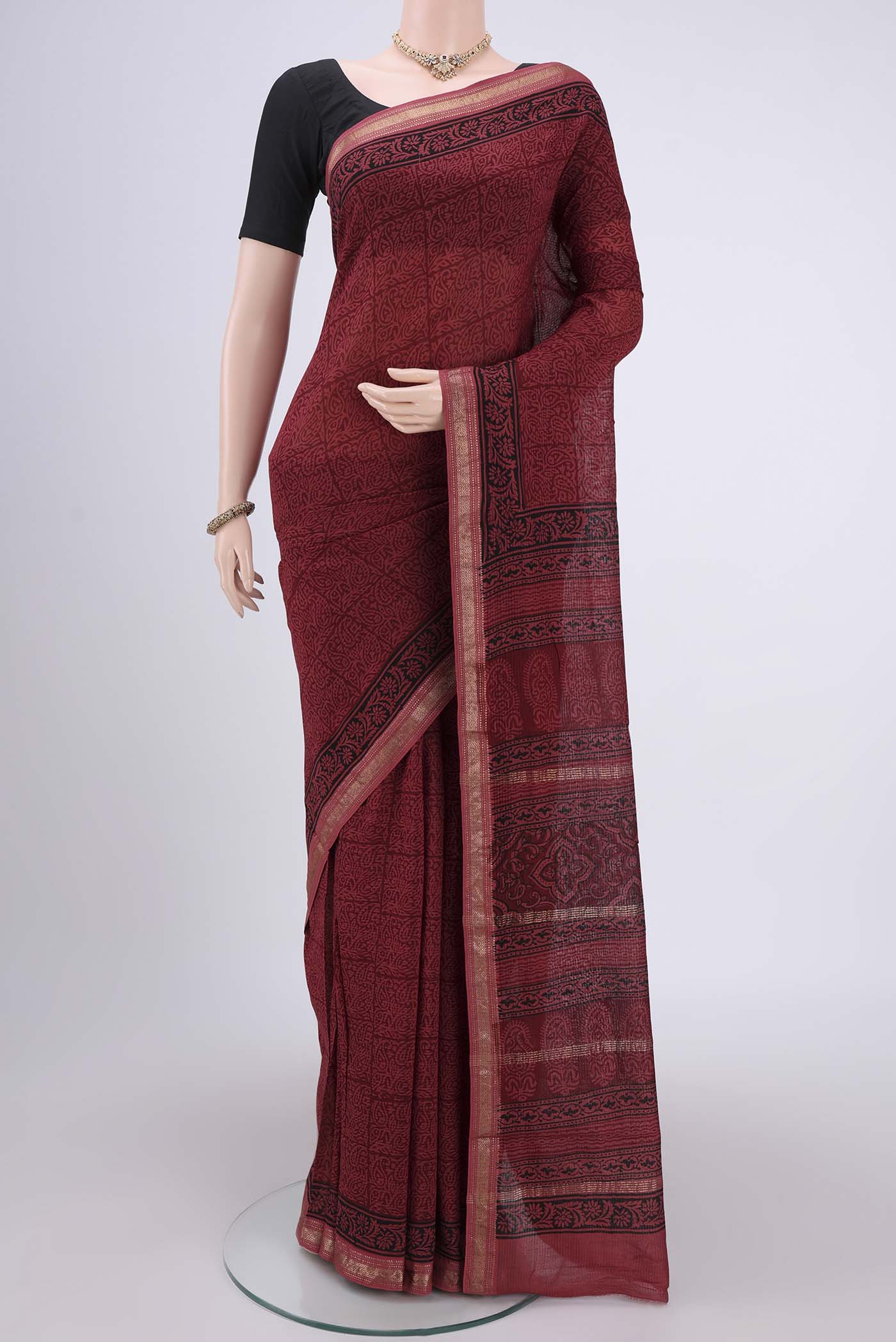 Maroon Maheshwari Silk Cotton Saree with Batik Print on the body and Zari Border.  displayed on a mannequin