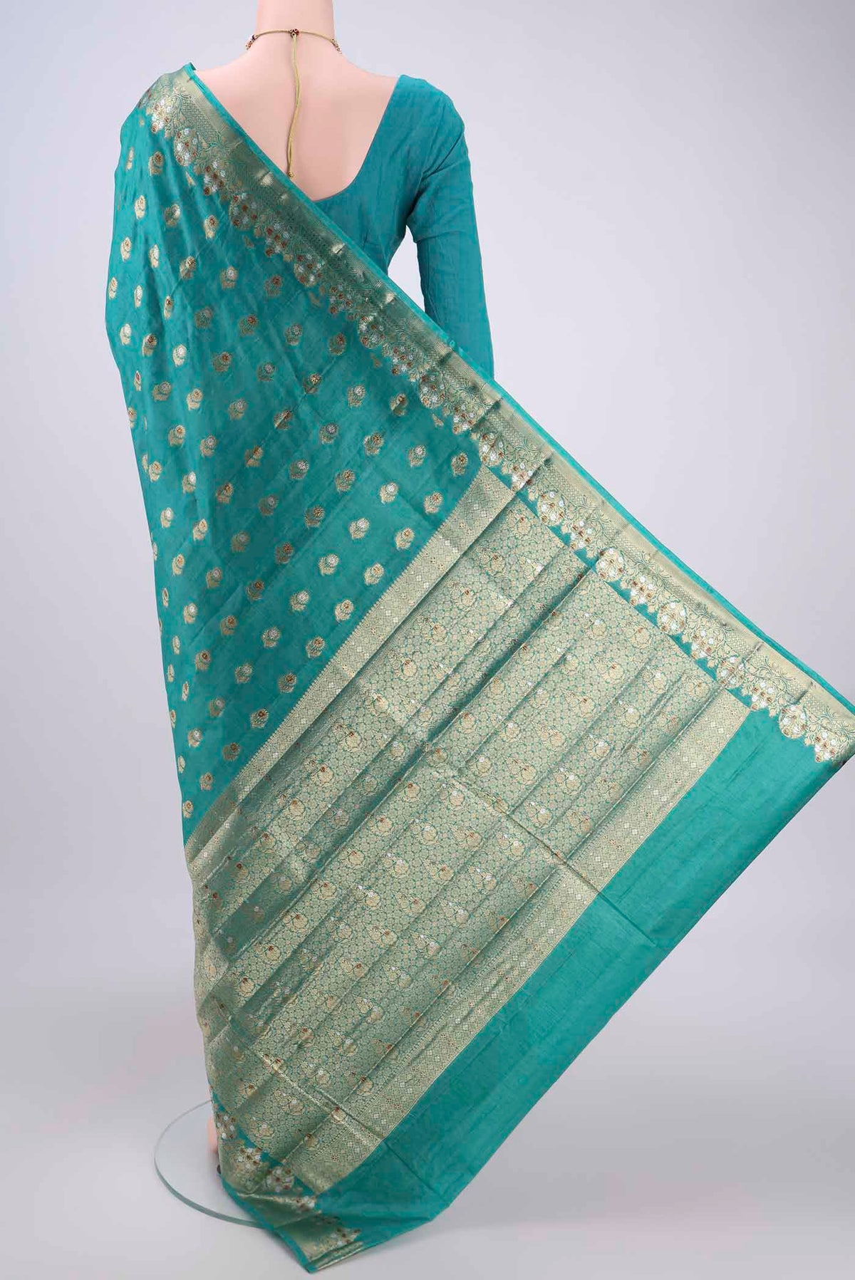 Flat view of Turquoise Banarasi Tussar Silk Saree with Zari And Thread Butta on the body and Zari And Thread Border. 