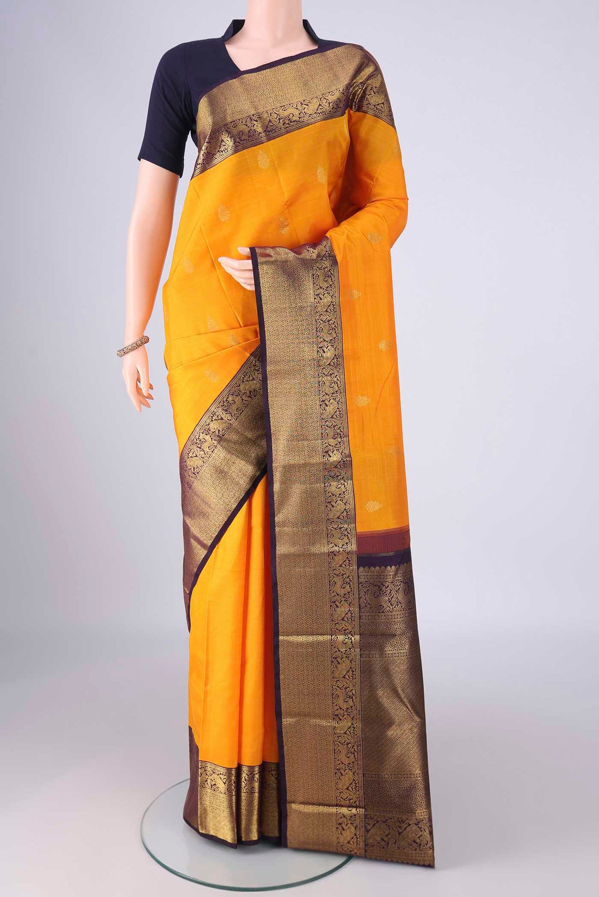 Yellow Kanchipuram Silk Saree with Zari Butta on the body and Zari Border.  displayed on a mannequin