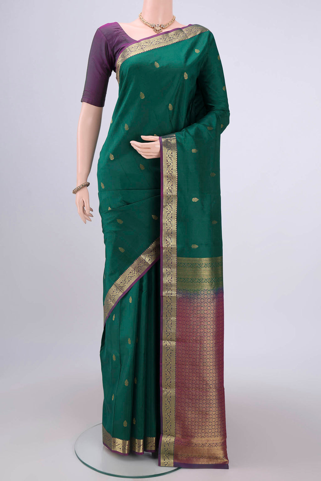 Bottle Green Kanjivaram Silk Saree with Zari Butta on the body and Zari Border.  displayed on a mannequin