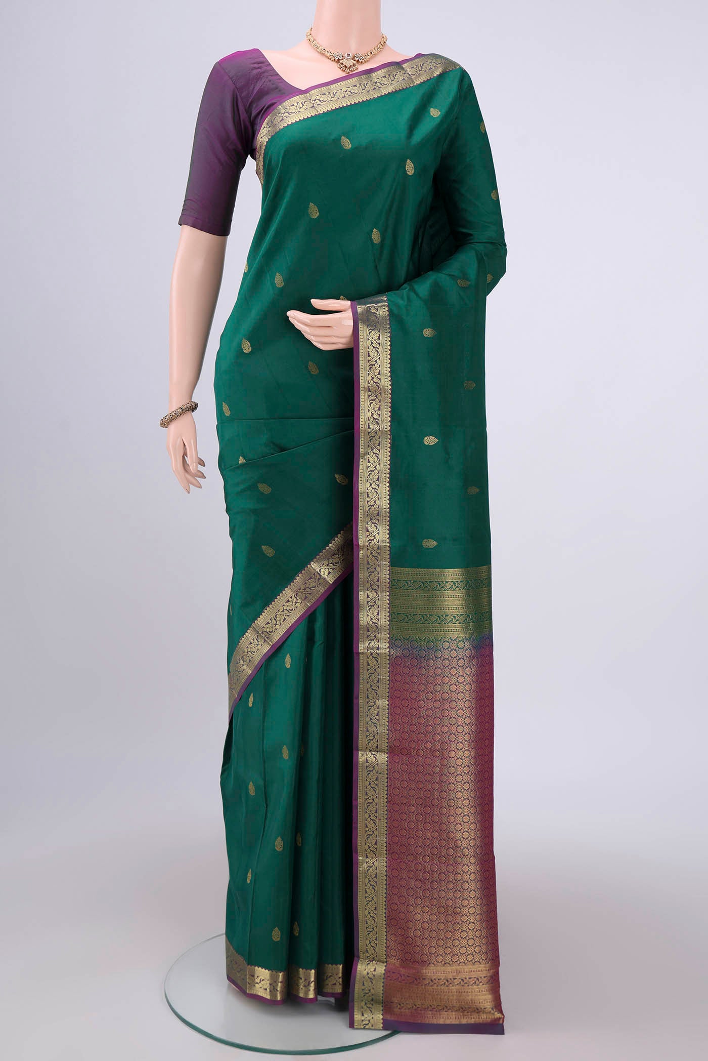 Bottle Green Kanjivaram Silk Saree with Zari Butta on the body and Zari Border.  displayed on a mannequin