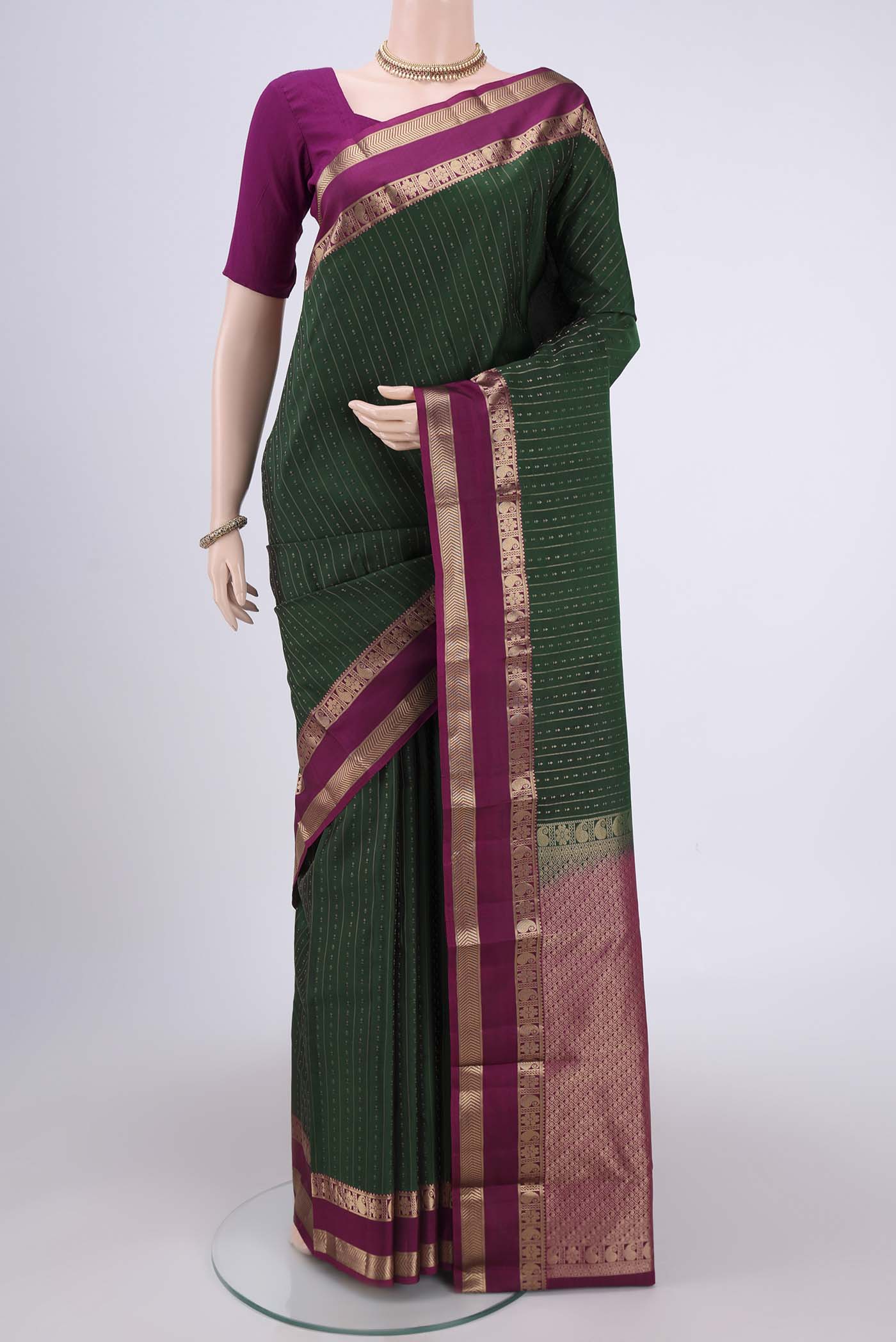Bottle Green Kanchipuram Silk Saree with Zari Butta on the body and Zari Border.  displayed on a mannequin