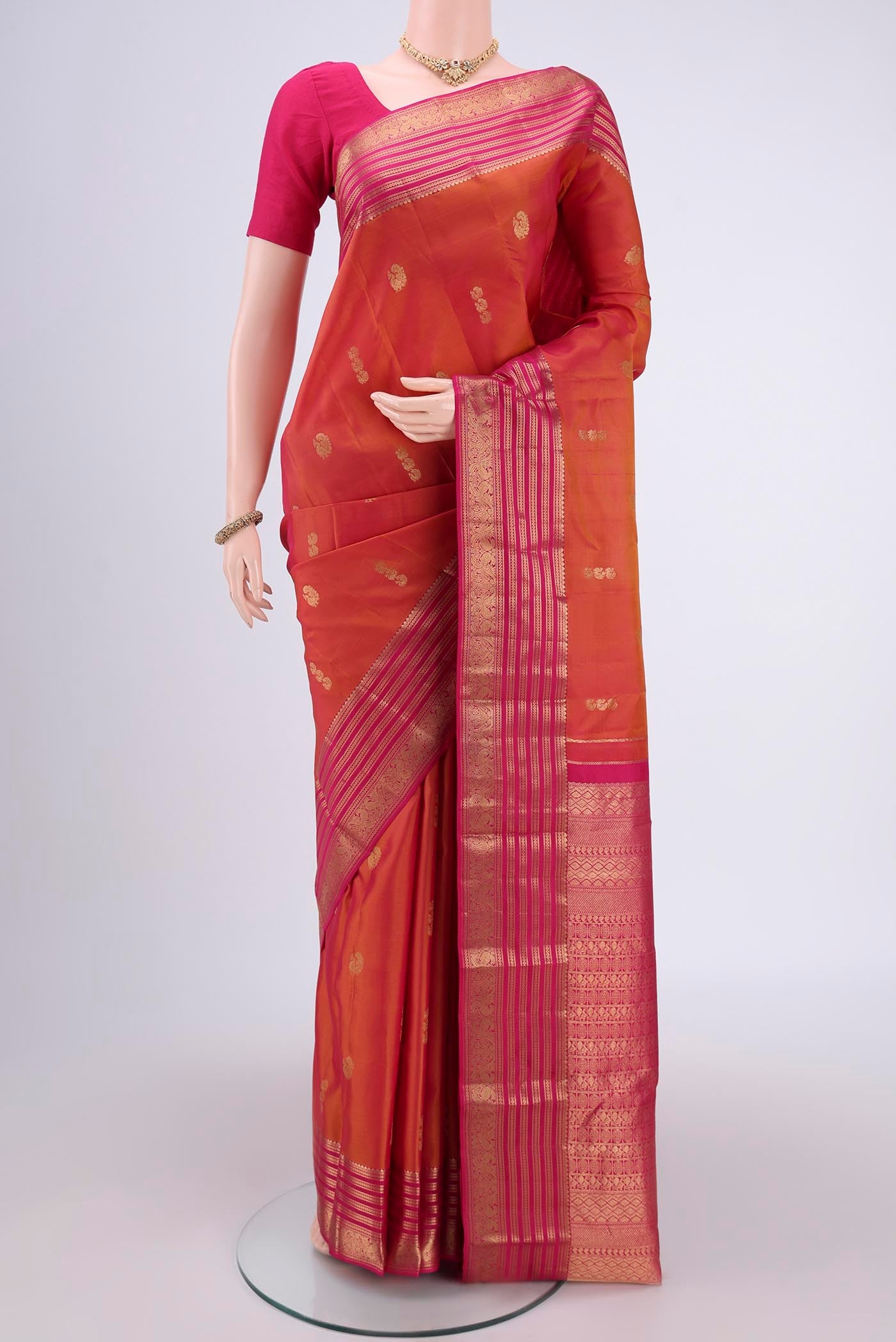 Brick Orange Kanchipuram Silk Saree with Zari Butta on the body and Zari Border.  displayed on a mannequin