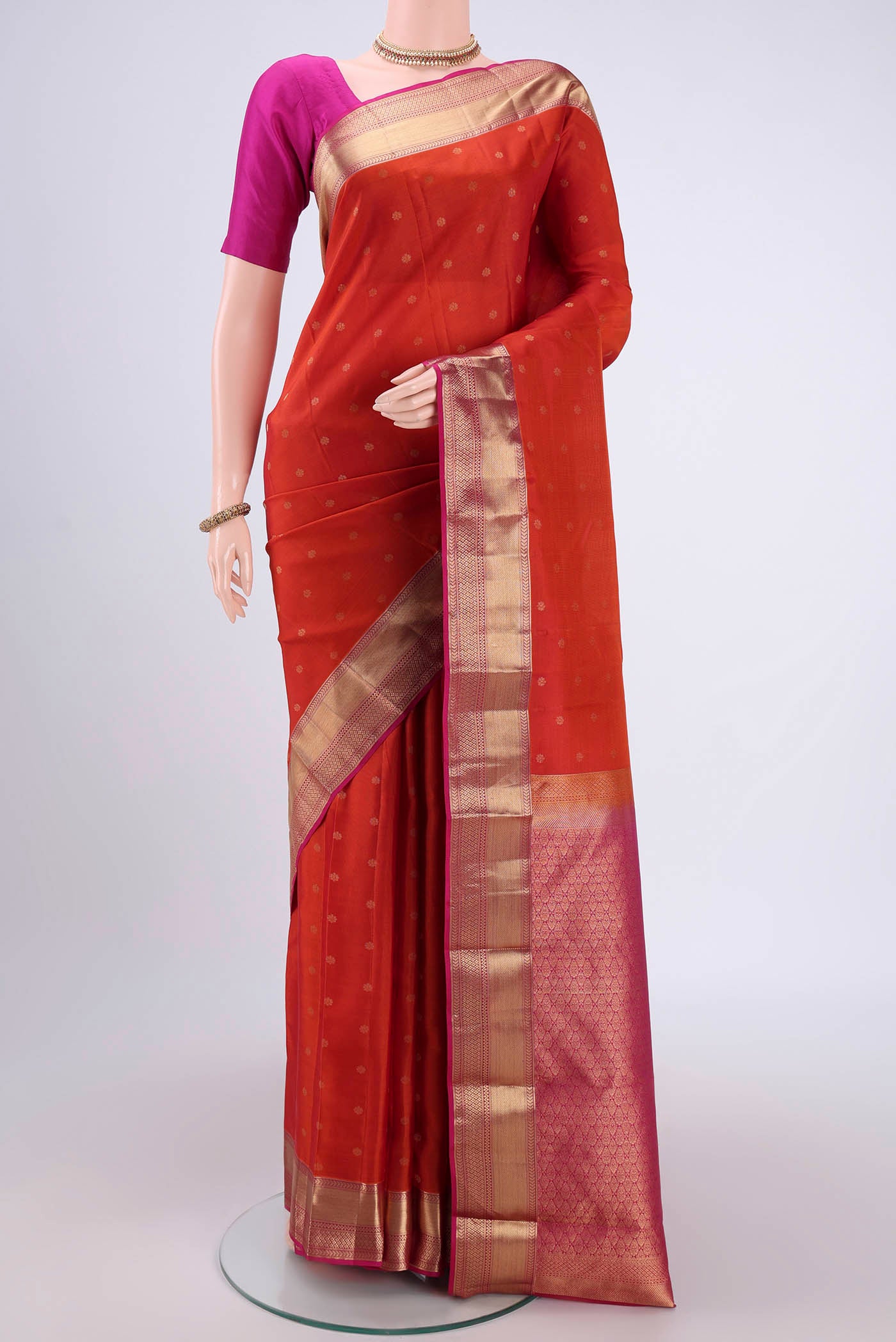 Orange Kanchipuram Silk Saree with Zari Butta on the body and Zari Border.  displayed on a mannequin