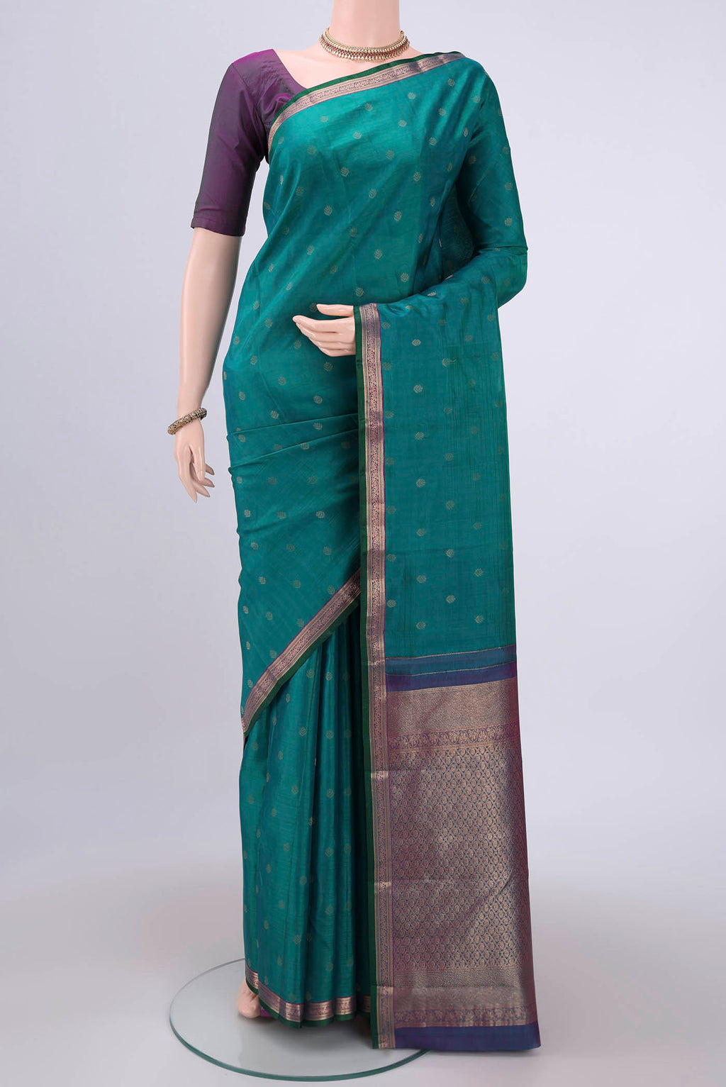 Green Kanchipuram Silk Saree with Zari Butta on the body and Zari Border.  displayed on a mannequin
