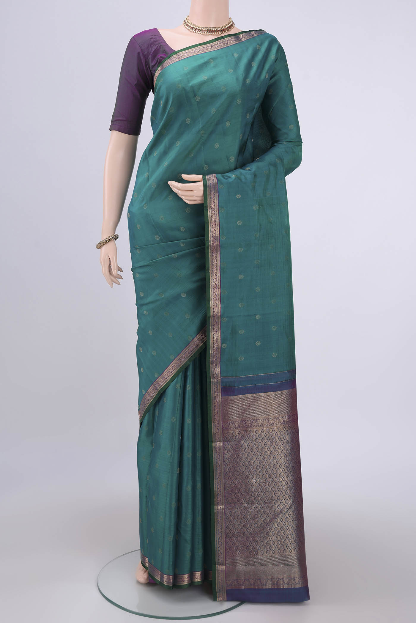 Green Kanchipuram Silk Saree with Zari Butta on the body and Zari Border.  displayed on a mannequin