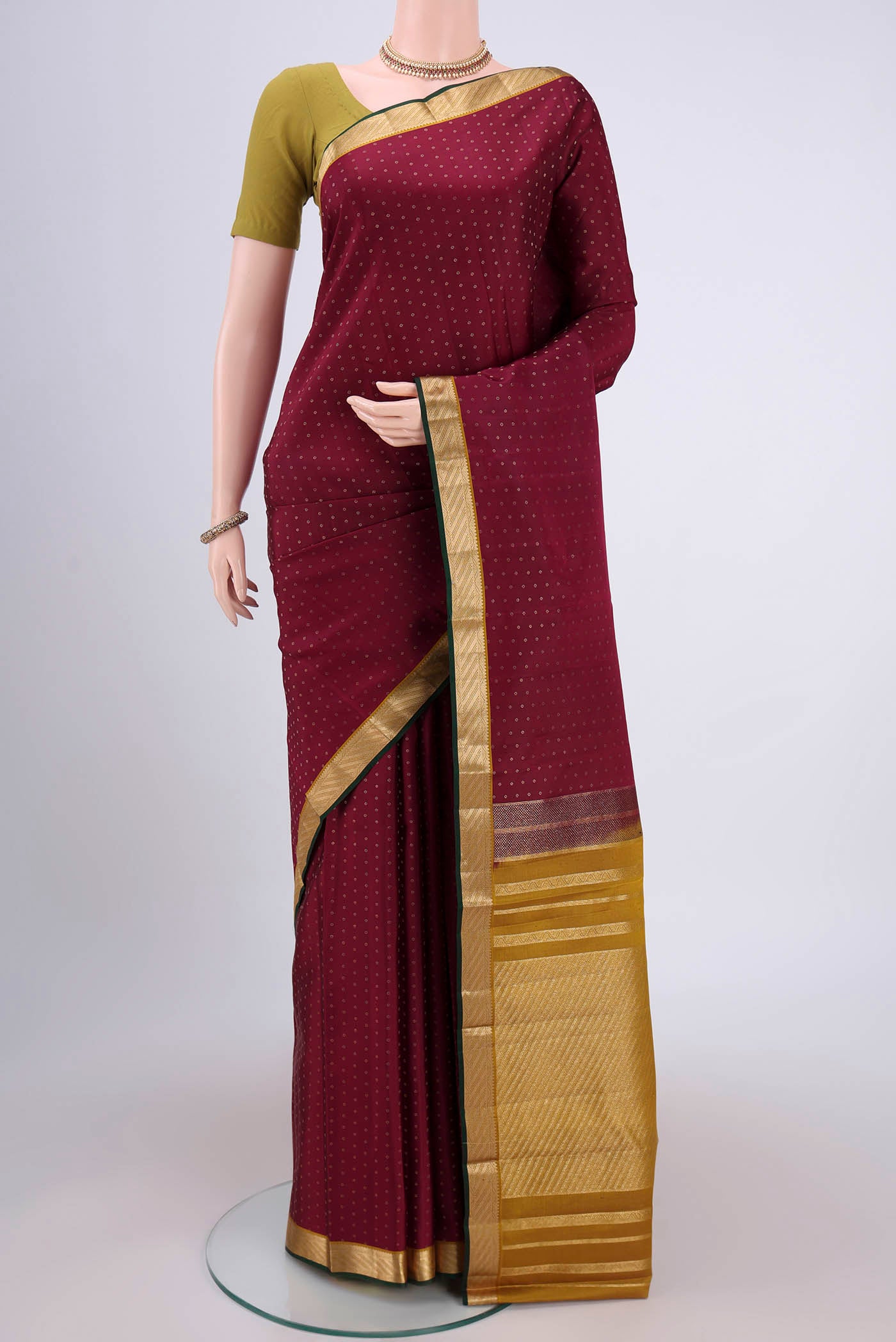Maroon Kanchipuram Silk Saree with Zari Butta on the body and Zari Border.  displayed on a mannequin