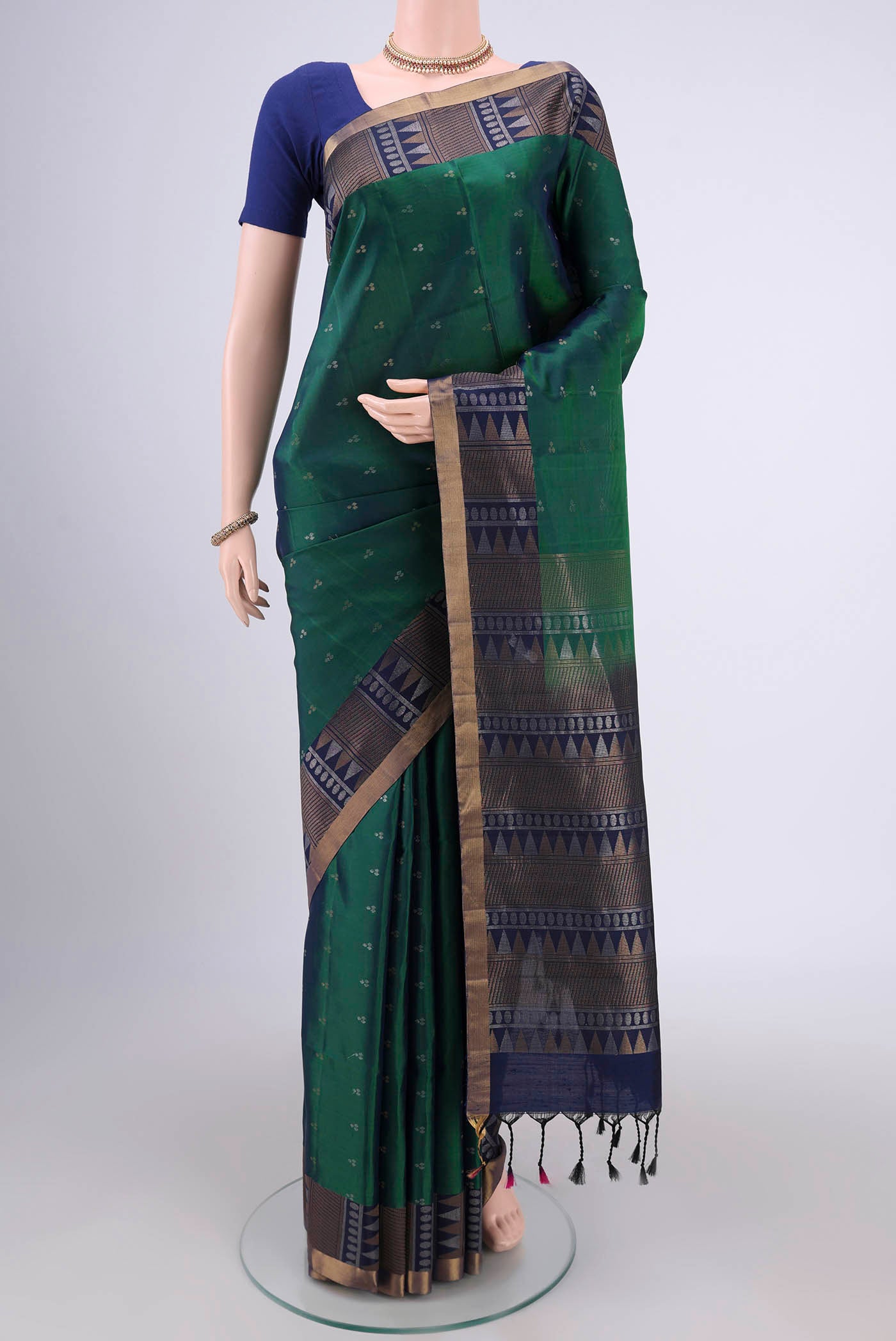 Bottle Green Soft Silk Saree with Zari Butta on the body and Zari Border.  displayed on a mannequin