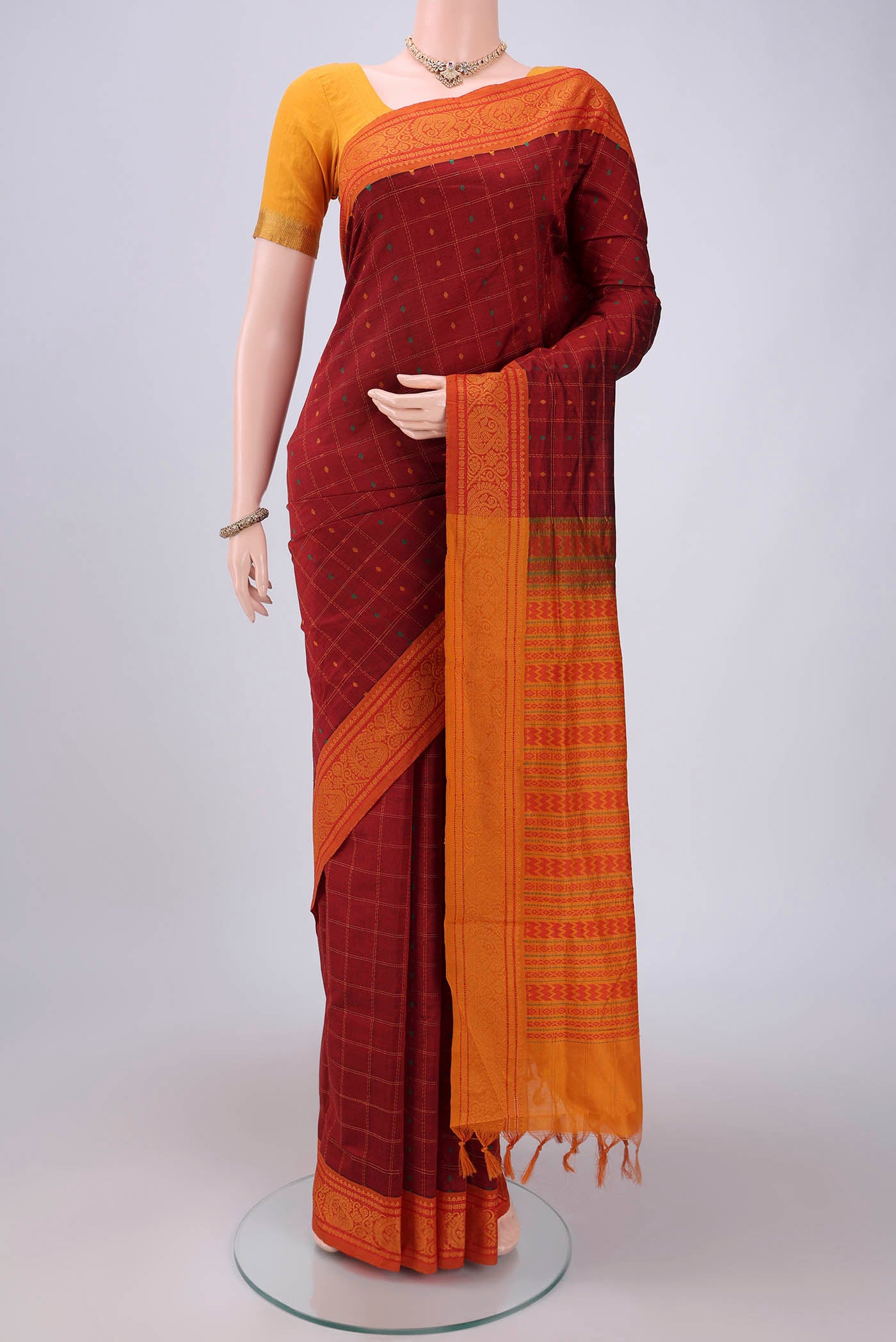 Maroon Blended Poly Cotton Saree with Checked design on the body and Thread Border.  displayed on a mannequin