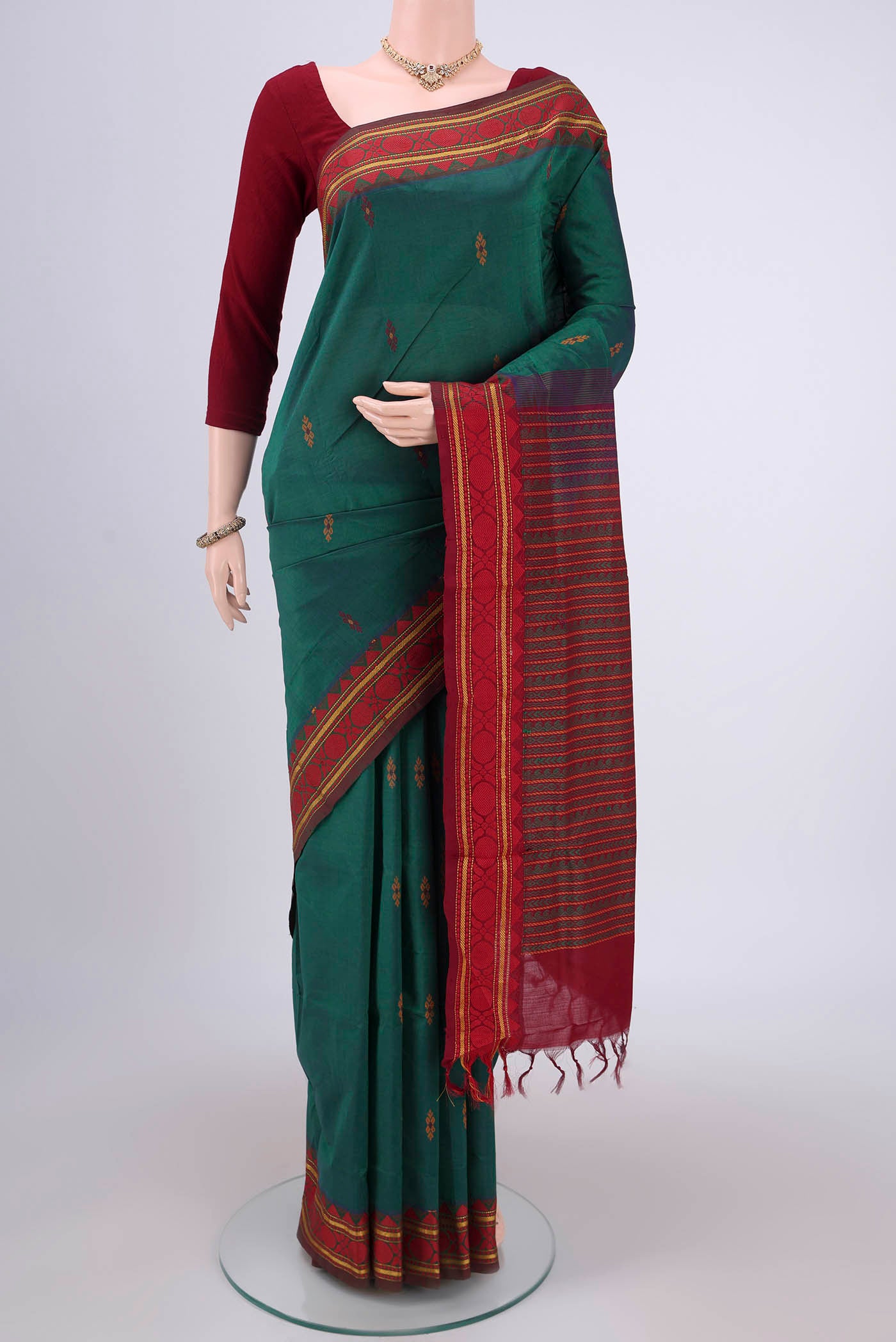 Bottle Green Blended Poly Cotton Saree with Thread Butta on the body and Thread Border.  displayed on a mannequin