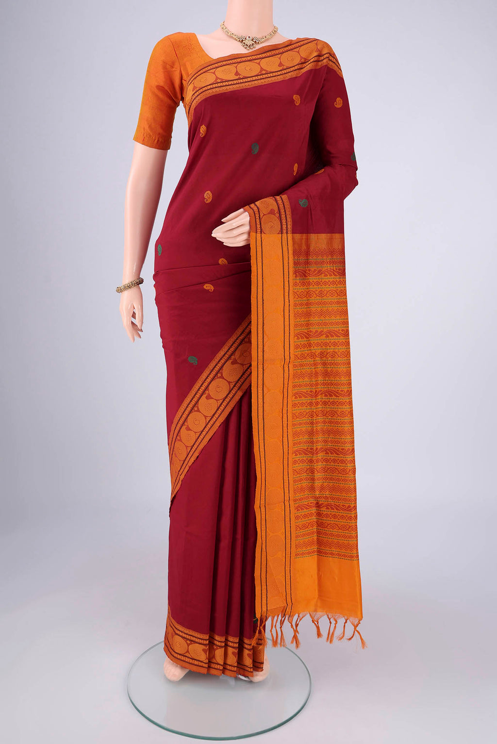 Maroon Blended Poly Cotton Saree with Thread Butta on the body and Thread Border.  displayed on a mannequin