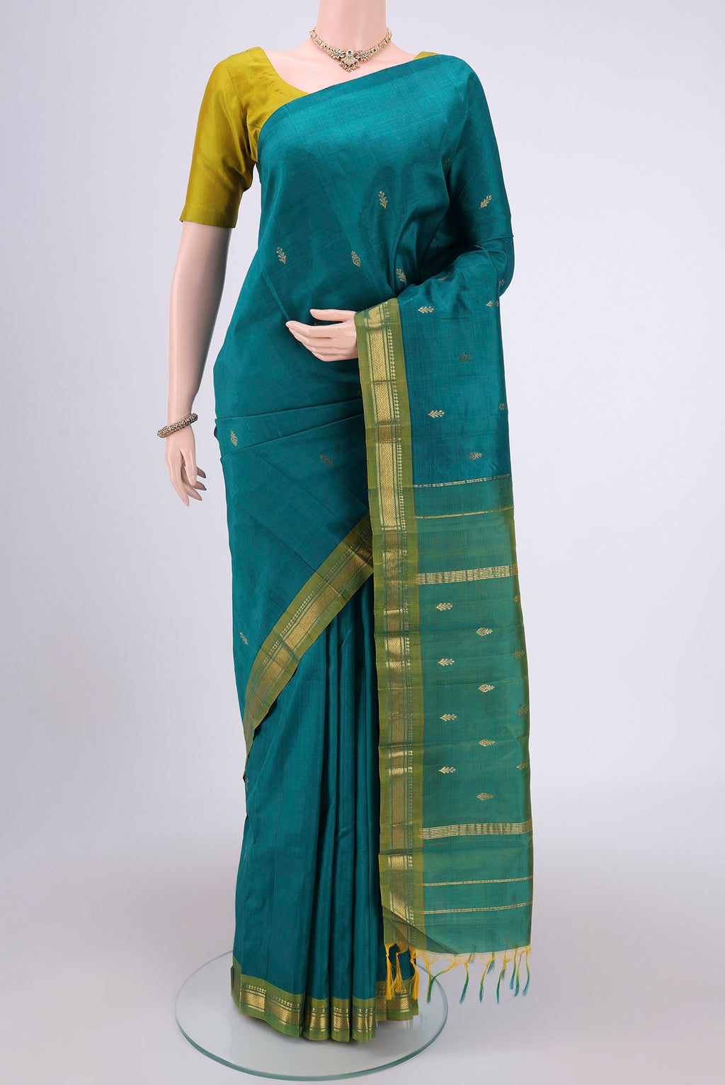 Green Kanchipuram Silk Saree with Zari Butta on the body and One Side Border.  displayed on a mannequin