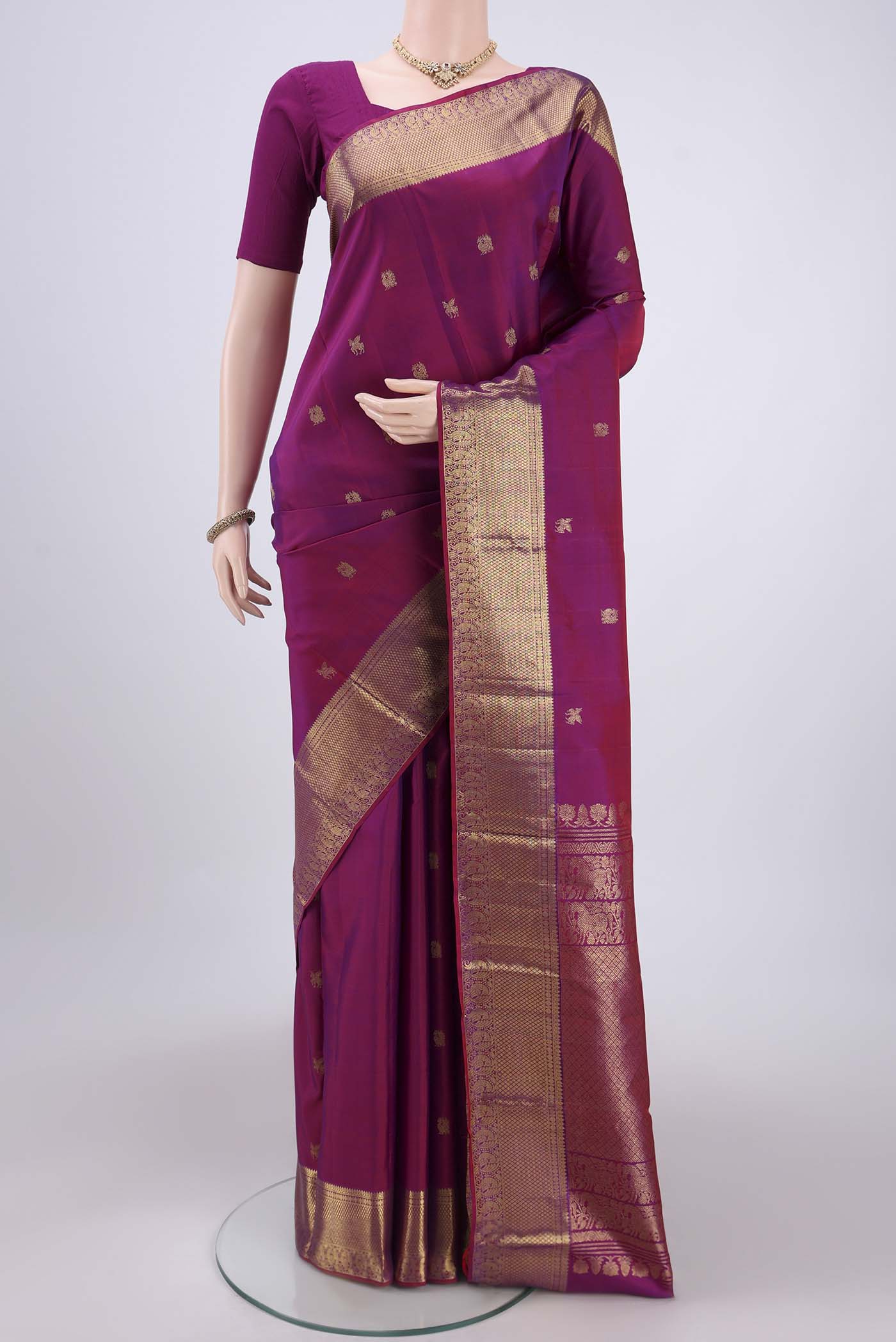 Magenta Kanjivaram Silk Saree with Zari Butta on the body and Zari Border.  displayed on a mannequin