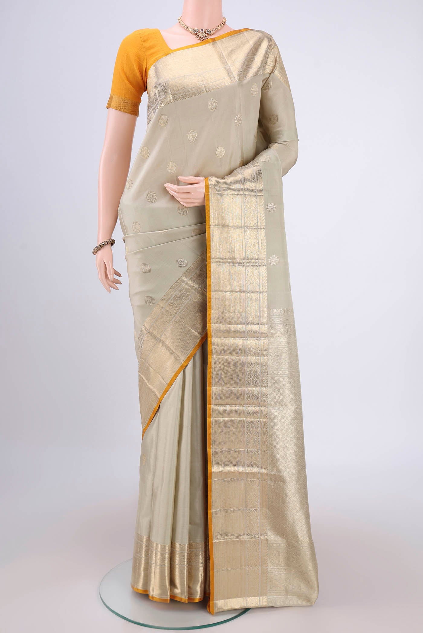 Sage Green Kanjivaram Silk Saree with Zari Butta on the body and Zari Border.  displayed on a mannequin