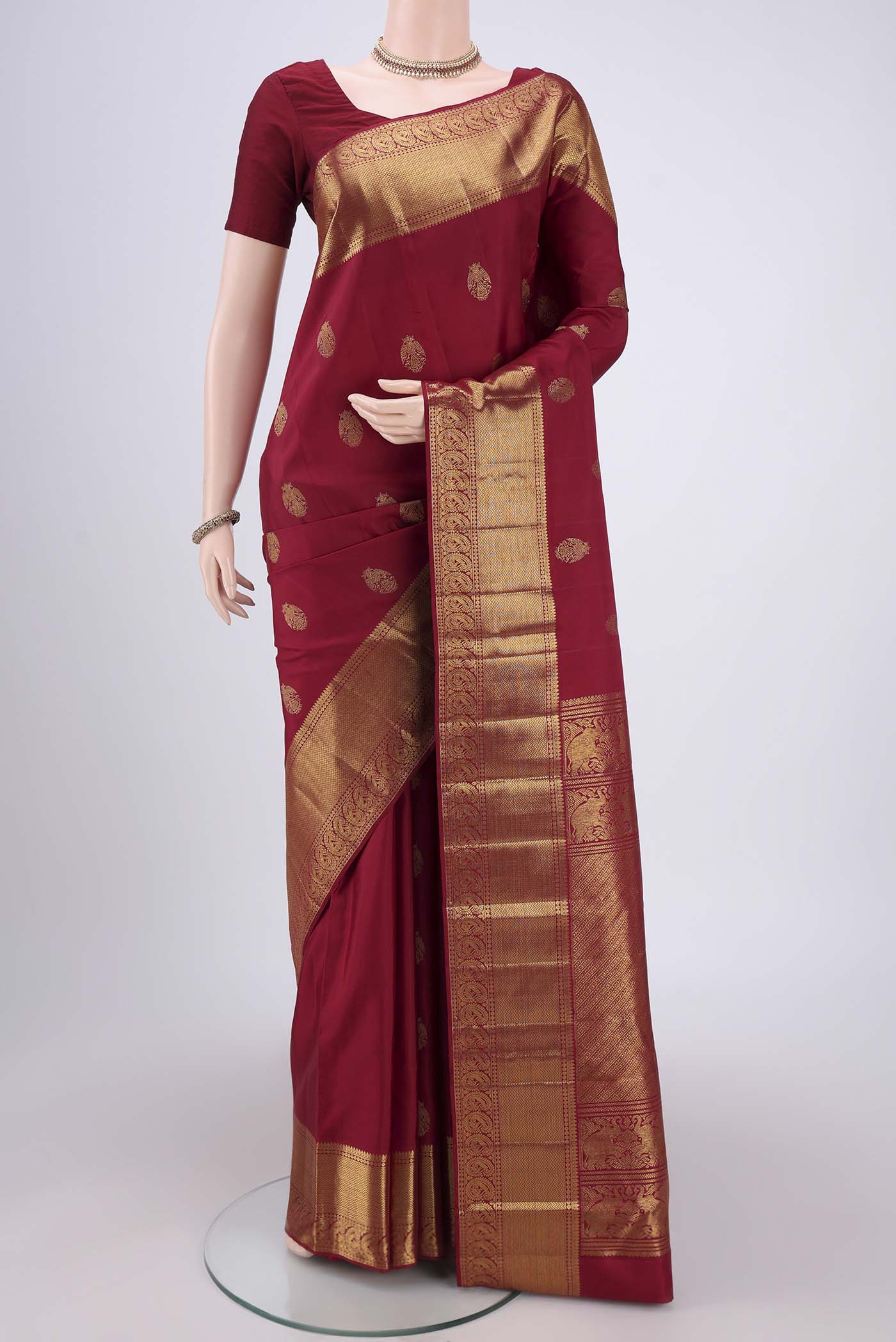 Maroon Kanjivaram Silk Saree with Zari Butta on the body and Zari Border.  displayed on a mannequin