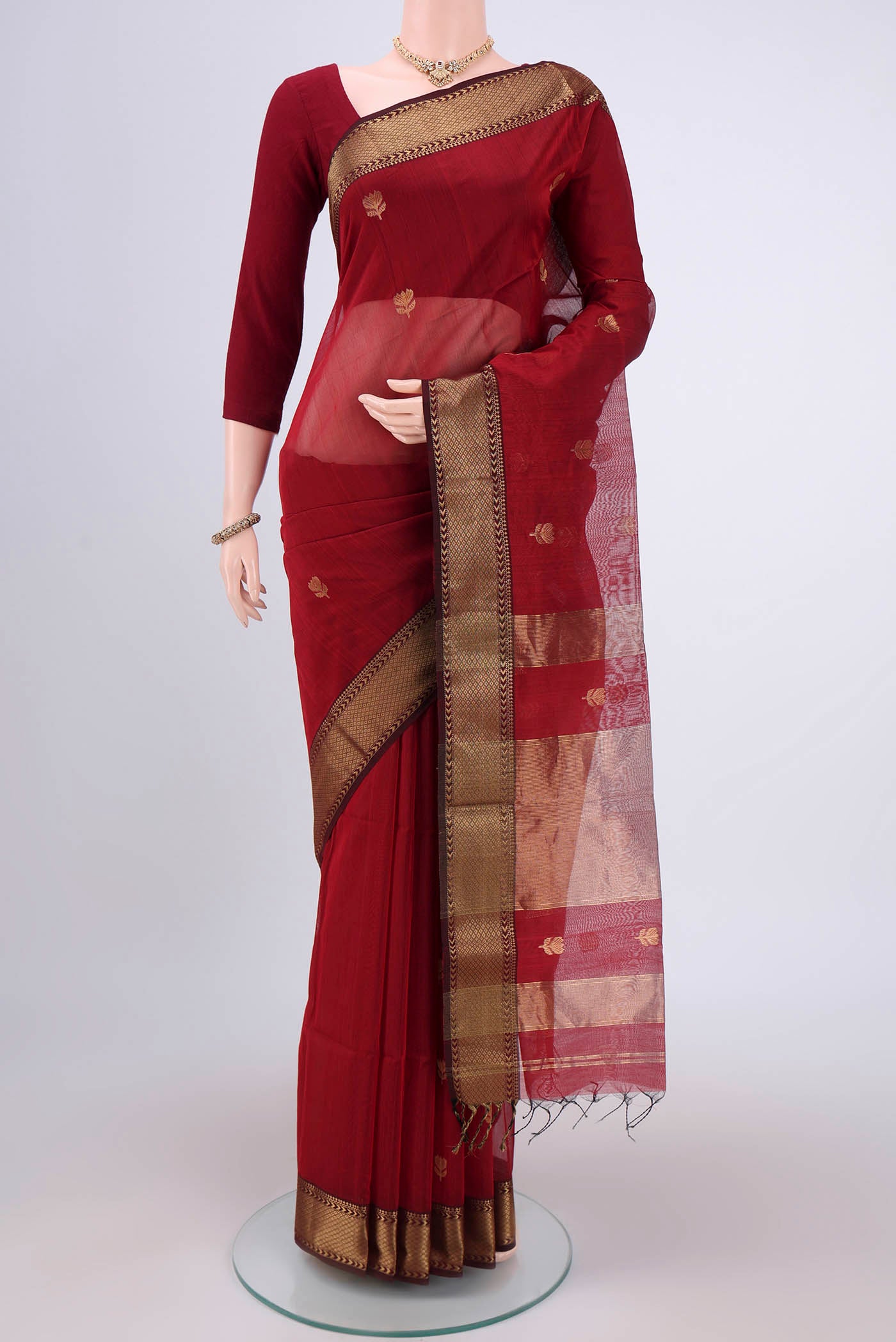 Maroon Maheshwari Silk Cotton Saree with Zari Butta on the body and Zari Border.  displayed on a mannequin