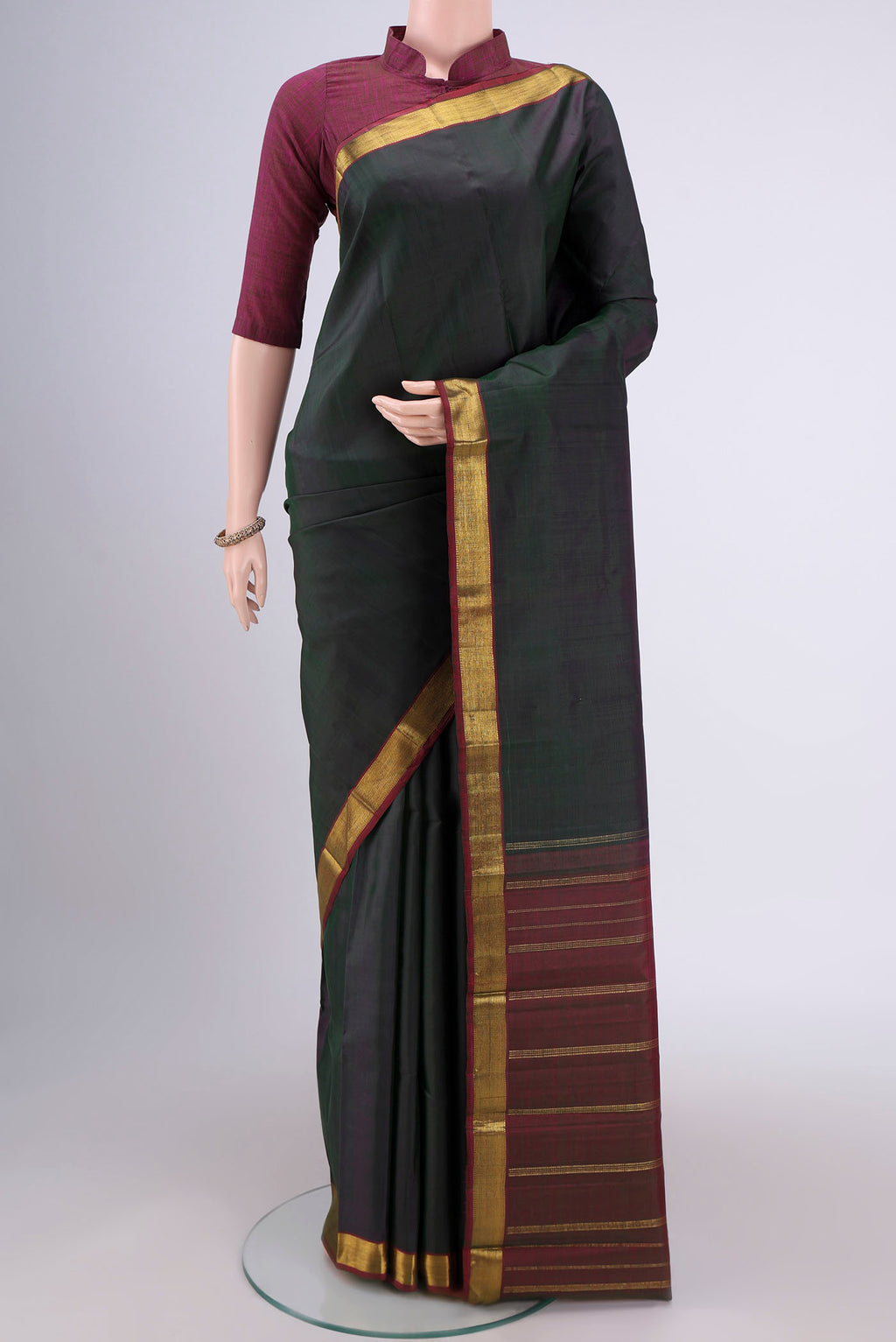 Bottle Green Kanjivaram Silk Saree with Plain Body and Zari Border.  displayed on a mannequin