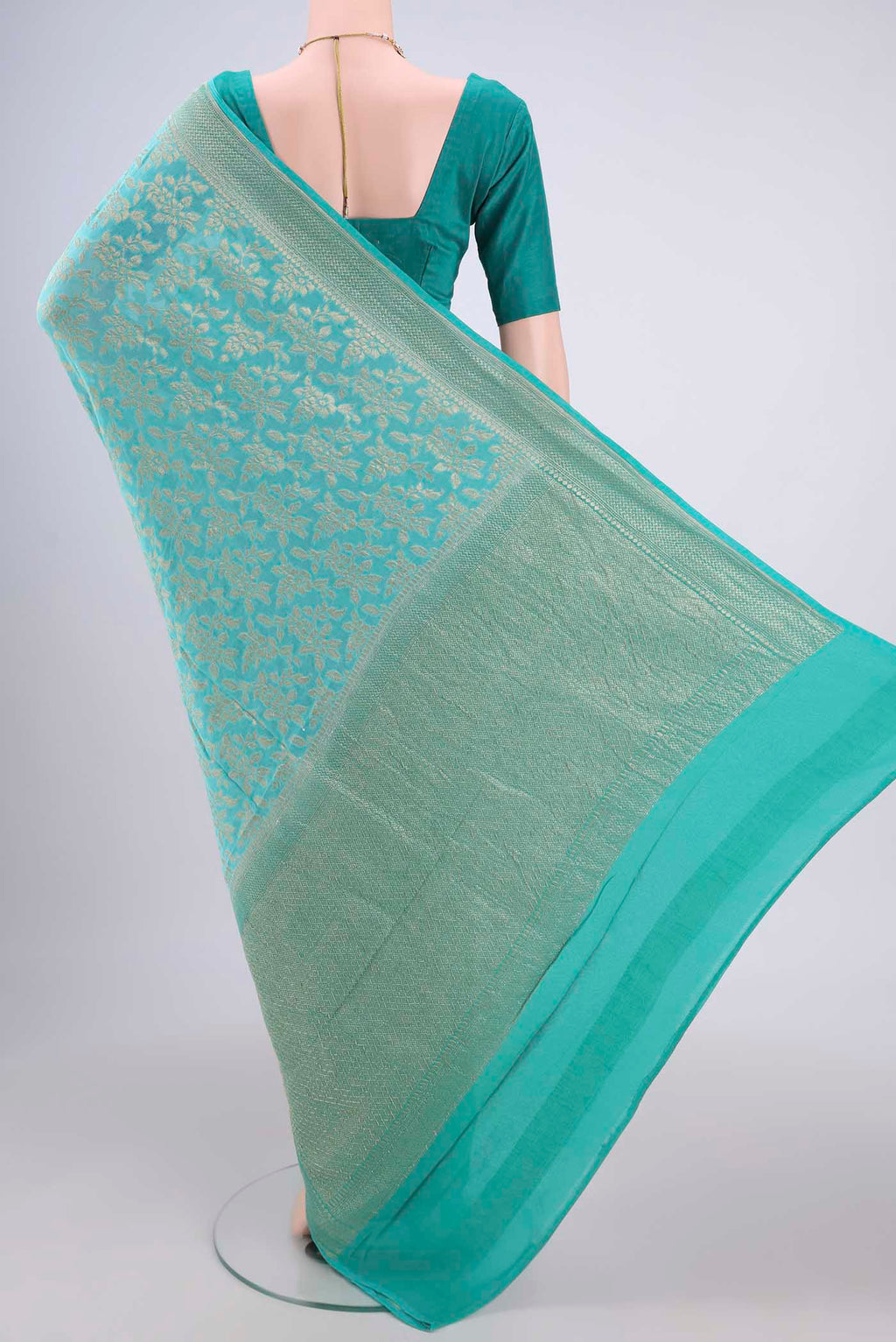 Flat view of Turquoise Banarasi Georgette Saree with Zari Brocade on the body and Zari Border. 