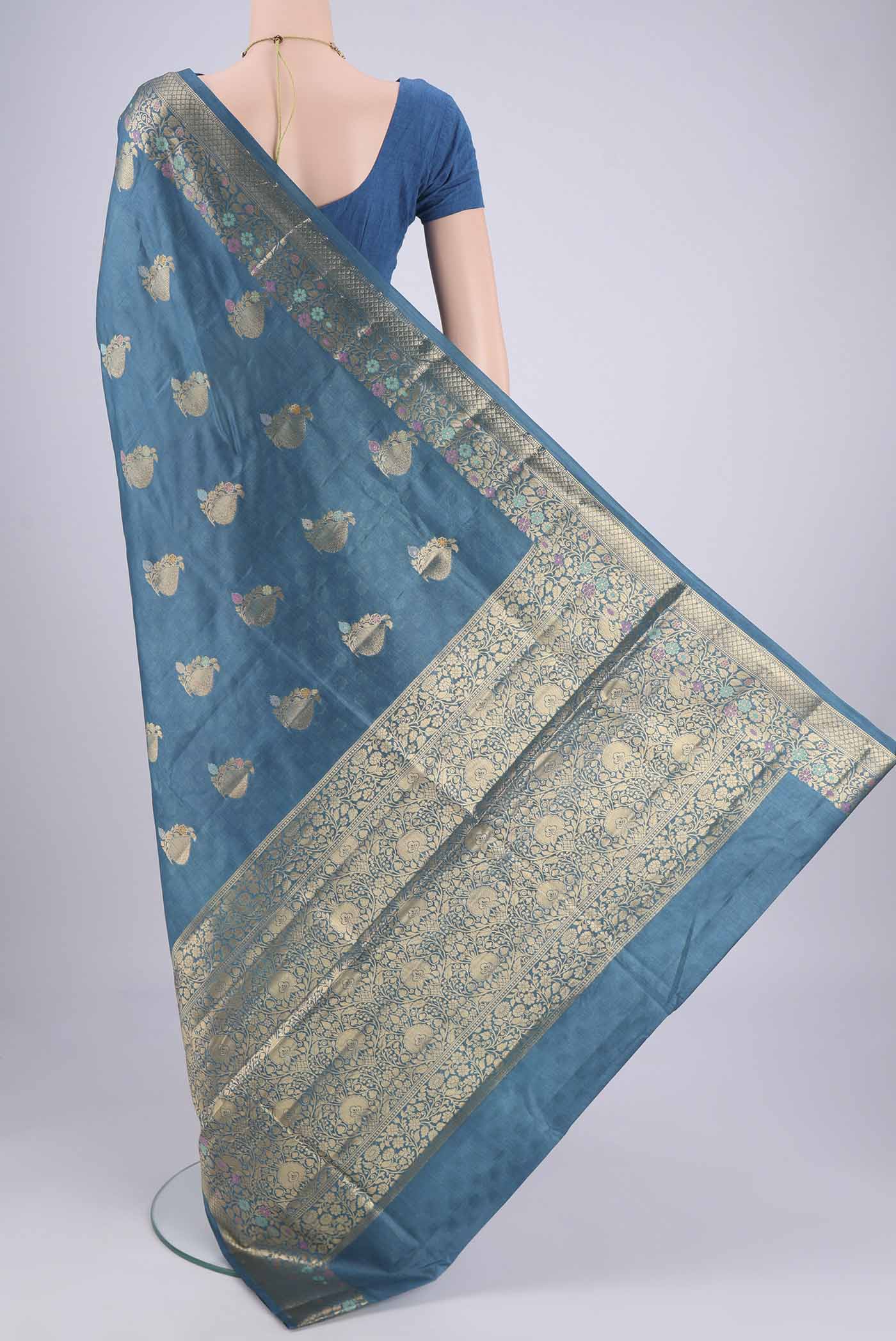 Flat view of Blue Banarasi Tussar Silk Saree with Zari And Thread Butta on the body and Zari And Thread Border. 