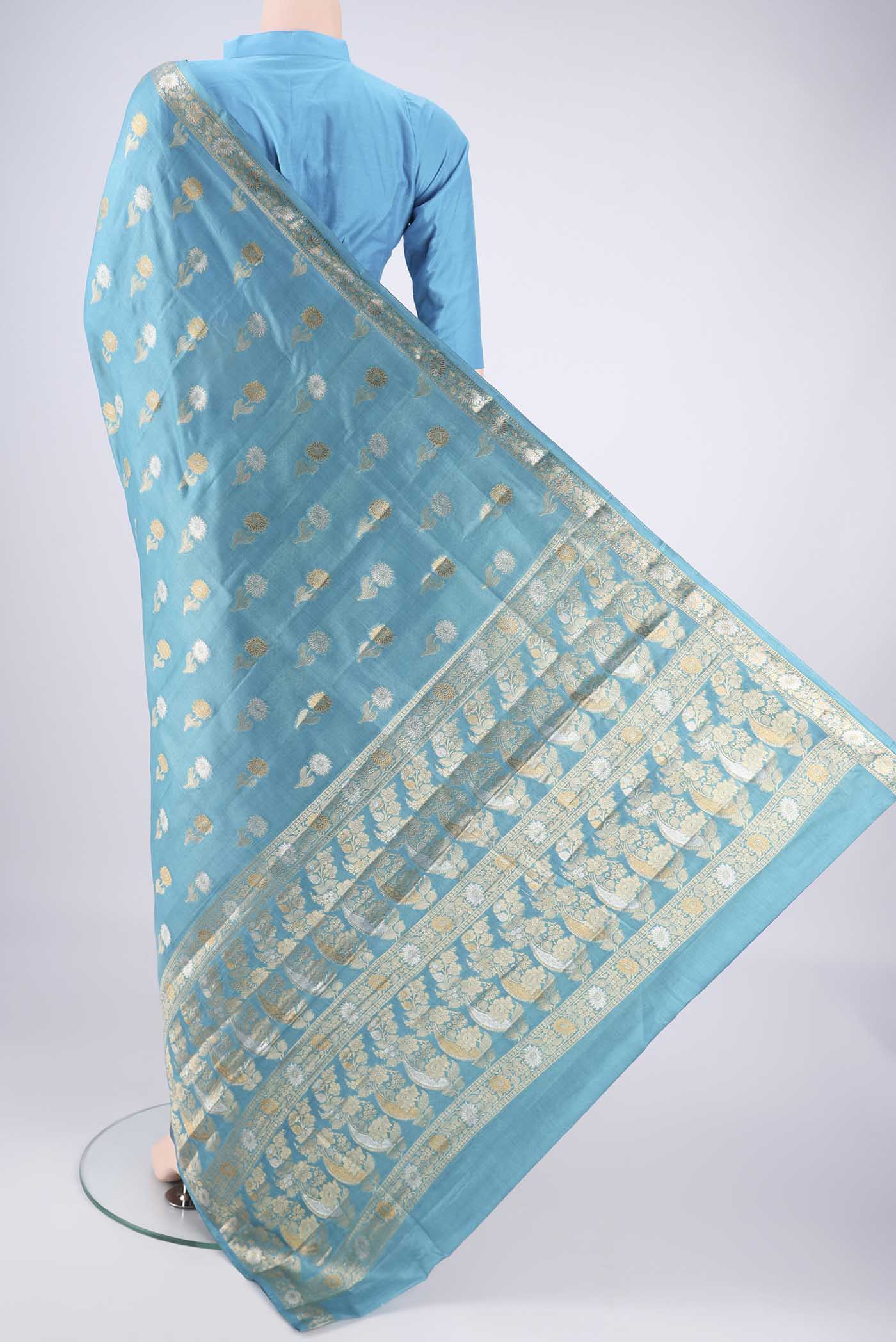 Flat view of Blue Banarasi Tussar Silk Saree with Zari Butta on the body and Zari Border. 