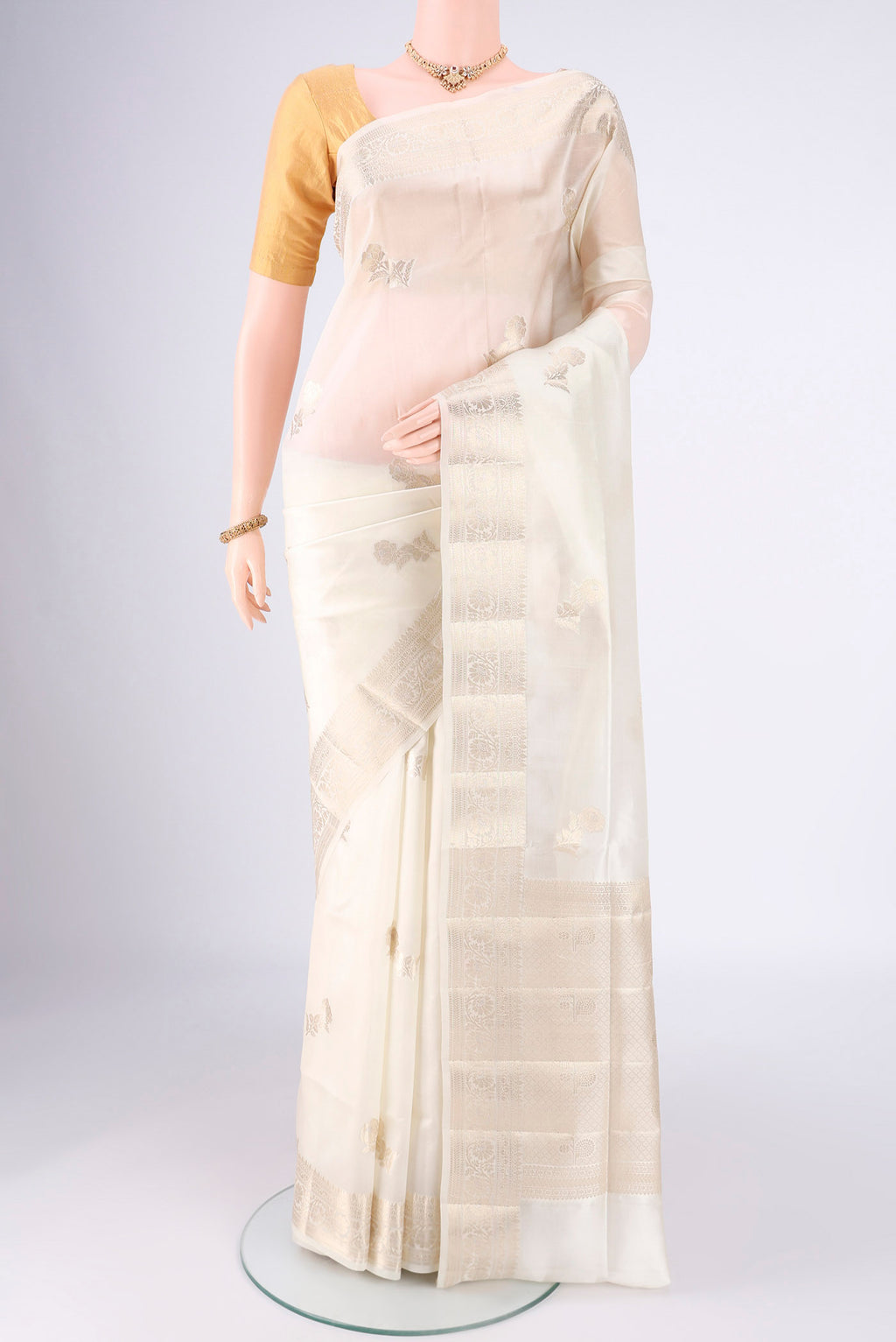 Off White Banarasi Raw Silk Saree with Zari Butta on the body and Zari Border.  displayed on a mannequin