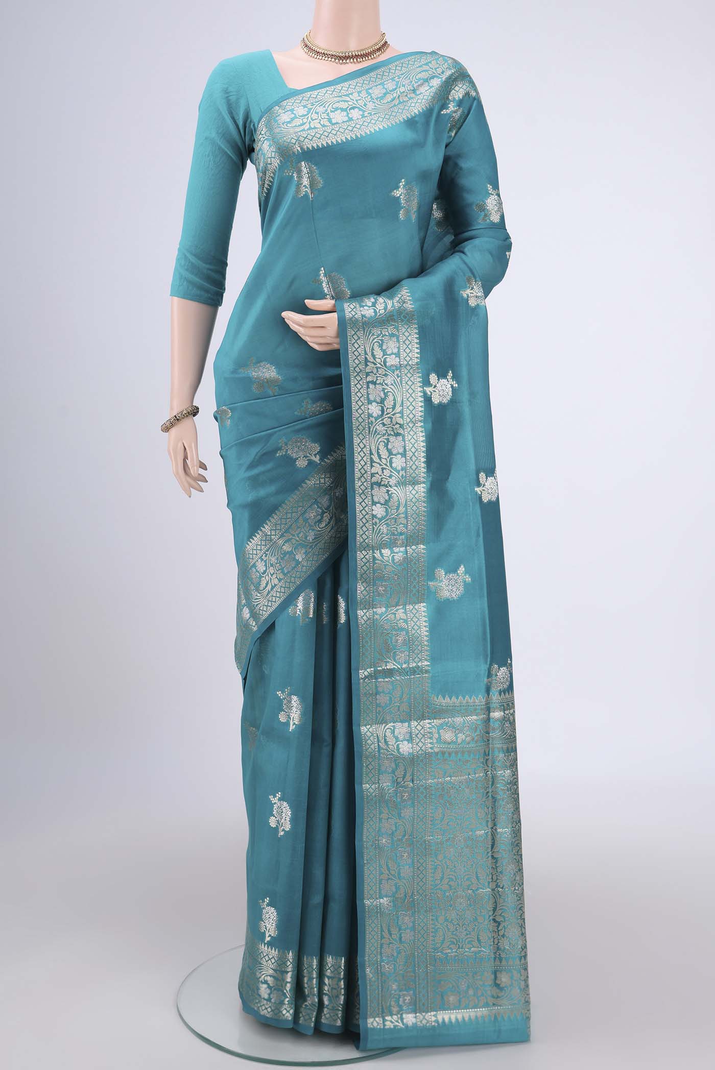 Teal Banarasi Raw Silk Saree with Zari Butta on the body and Zari Border.  displayed on a mannequin
