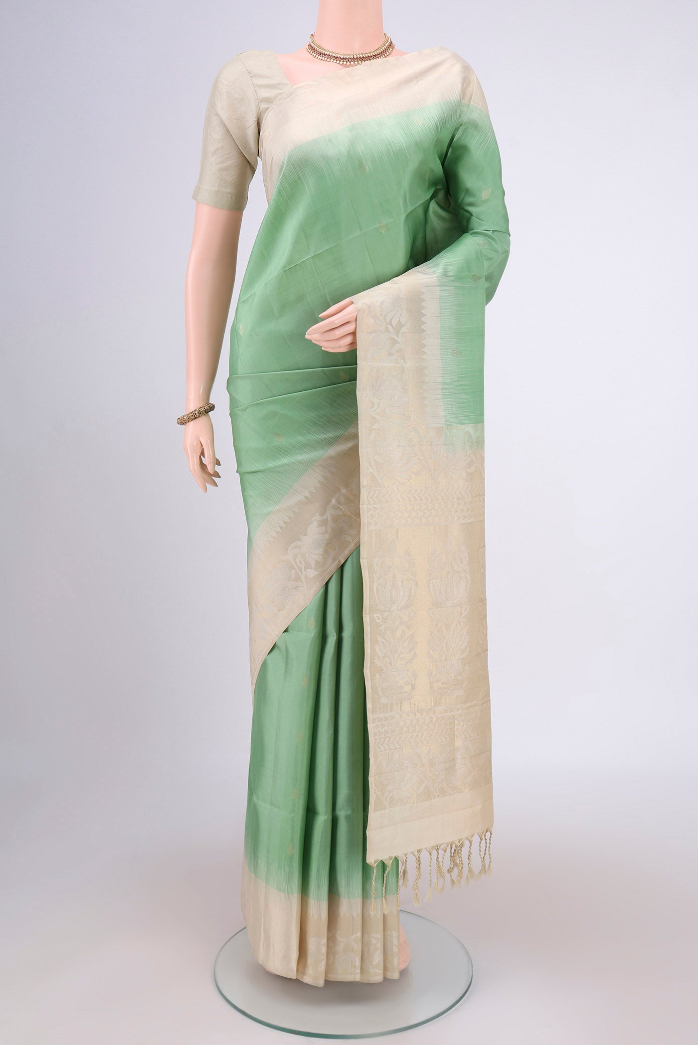Light Green Soft Silk Saree with Zari Butta on the body and Zari Border.  displayed on a mannequin