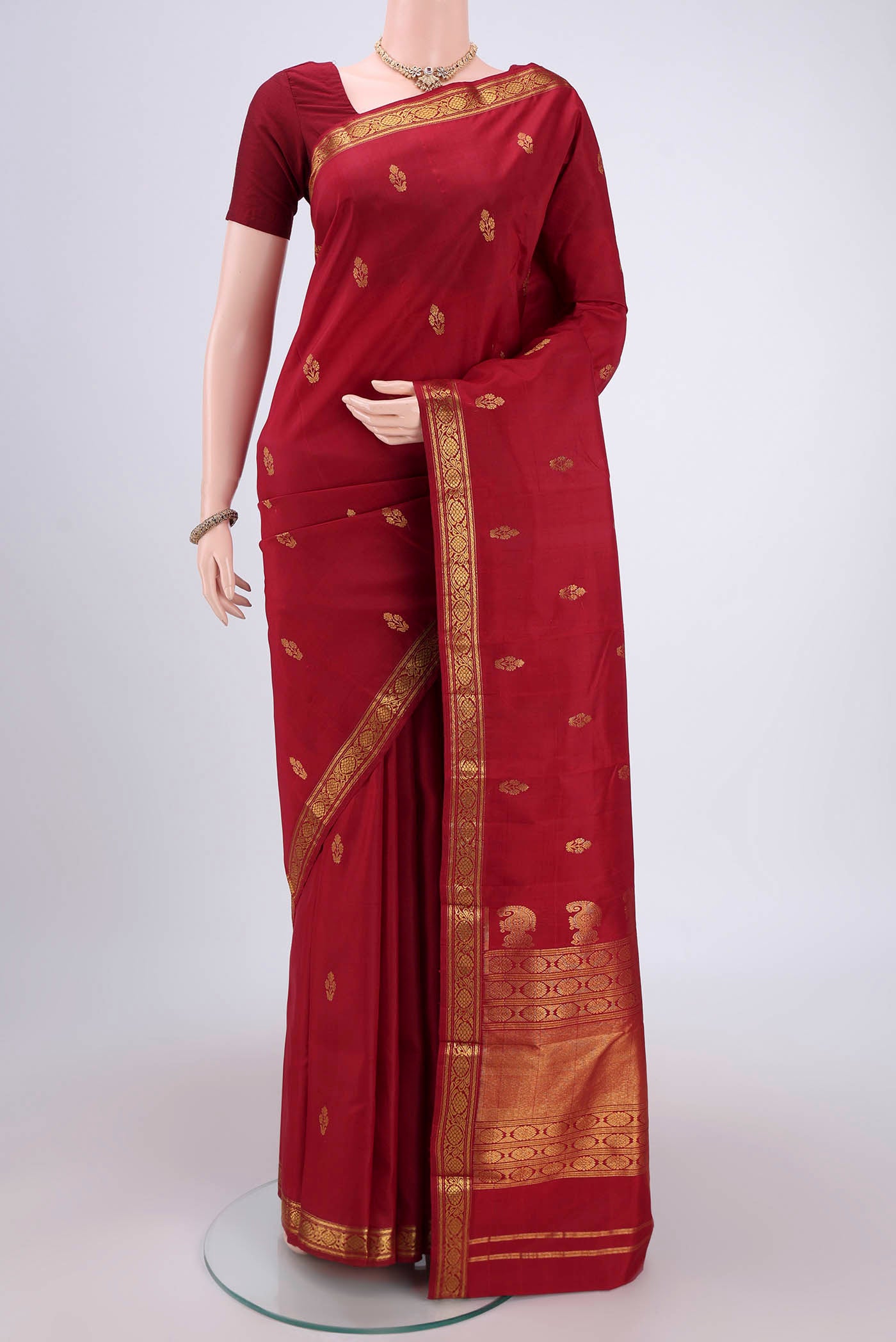 Maroon Kanjivaram Silk Saree with Zari Butta on the body and Zari Border.  displayed on a mannequin