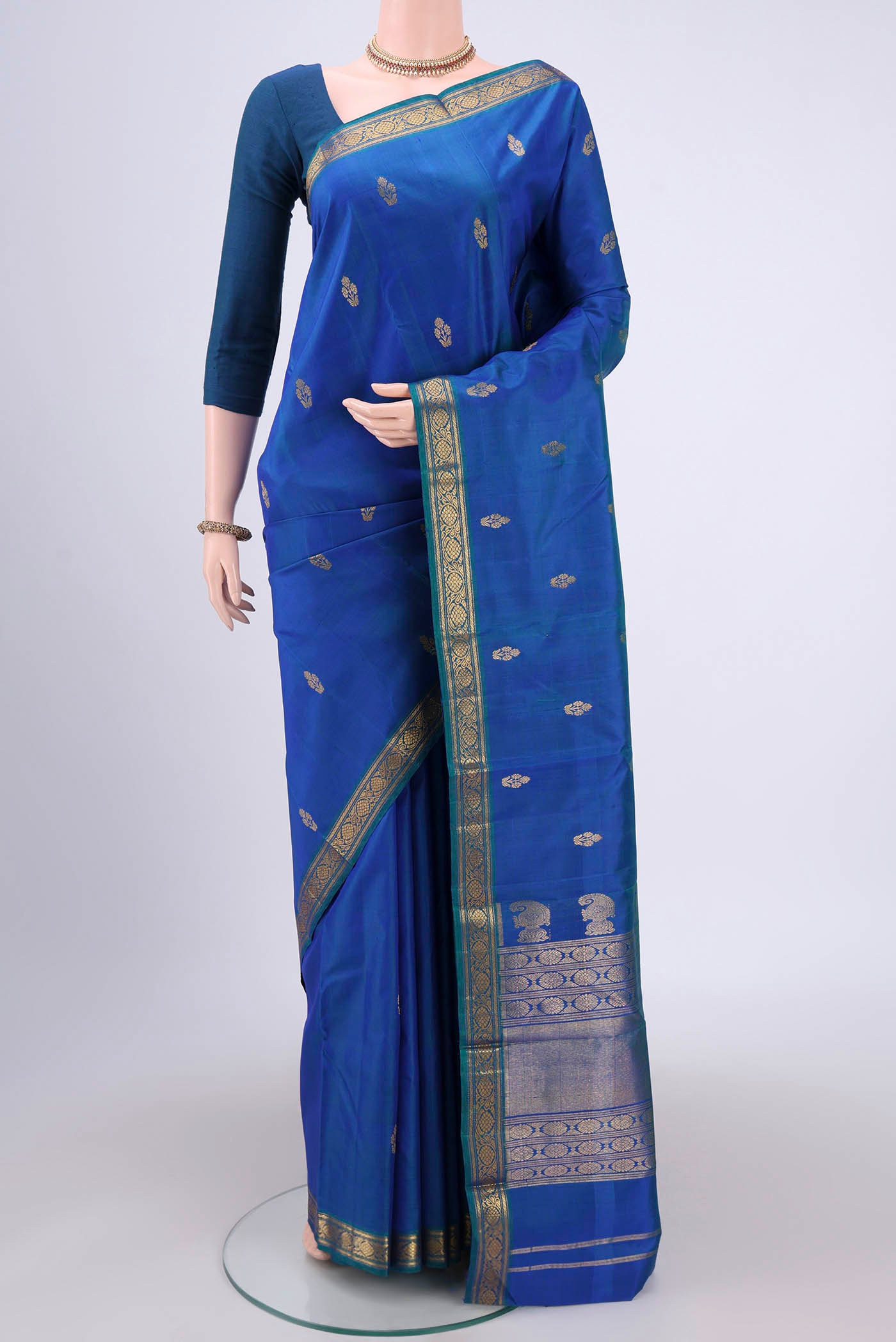 Turquoise Kanjivaram Silk Saree with Zari Butta on the body and Zari Border.  displayed on a mannequin