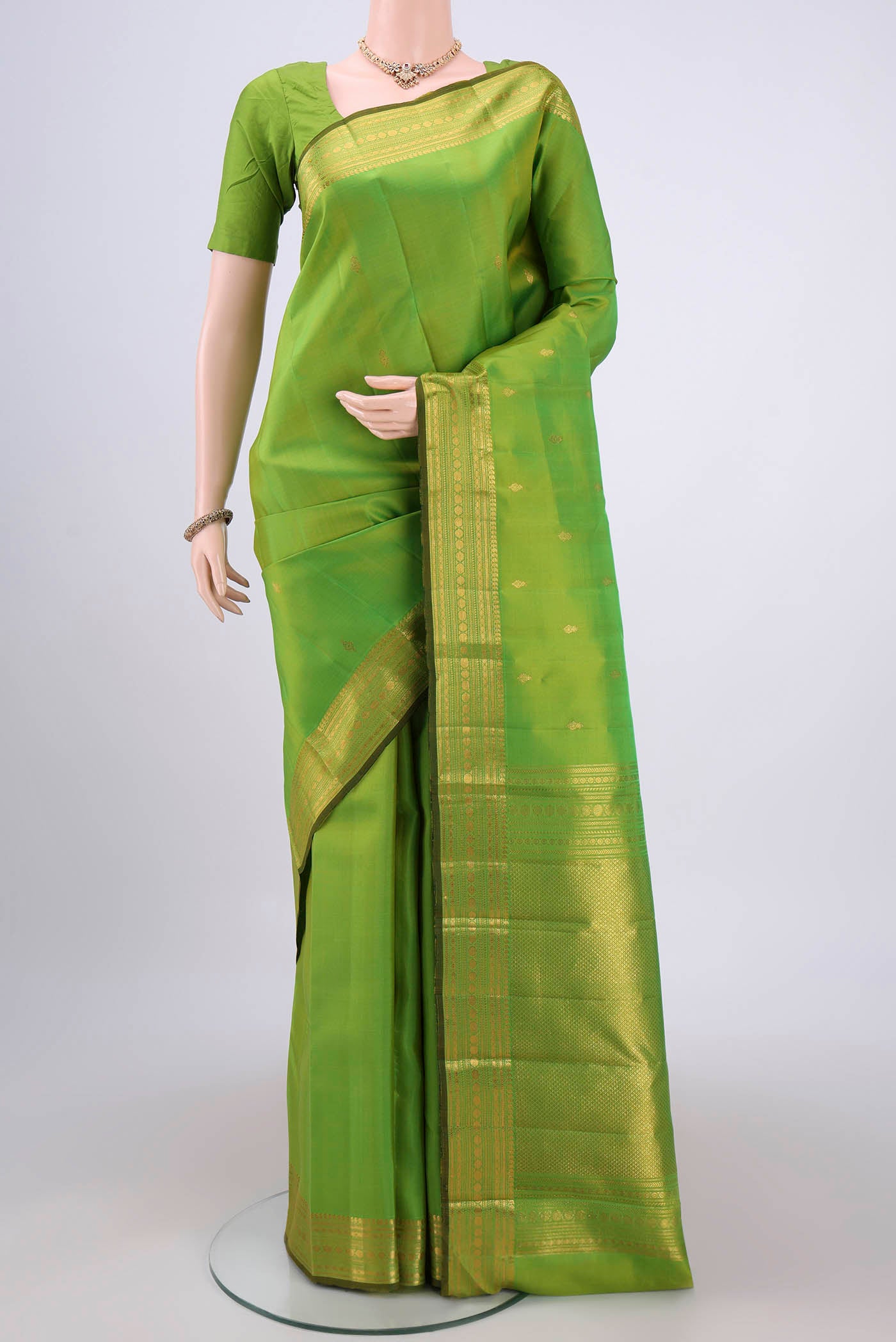 Parrot Green Kanjivaram Silk Saree with Zari Butta on the body and Zari Border.  displayed on a mannequin